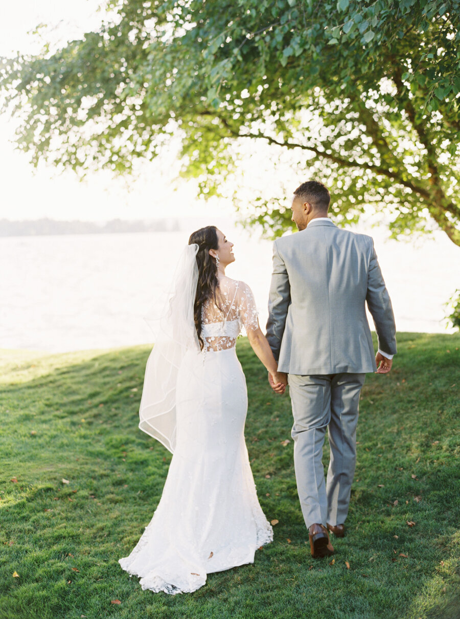 bride and groom walking away at lake front wedding