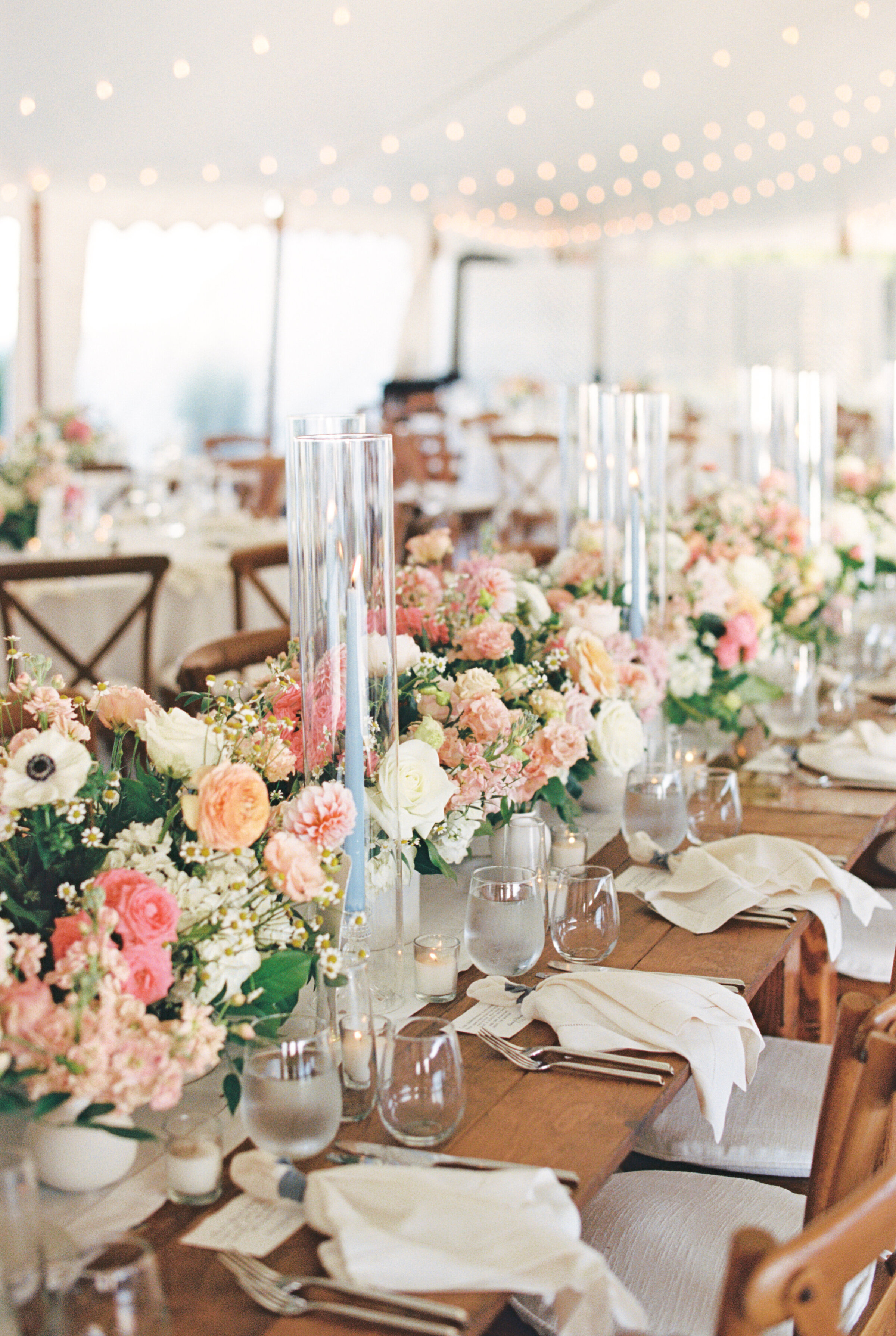 lush flowers and taper candles along a long farm table for a tented wedding at Mount Hope Farm