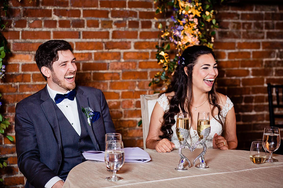 Couple laughing together at their sweetheart table during cocktail hour