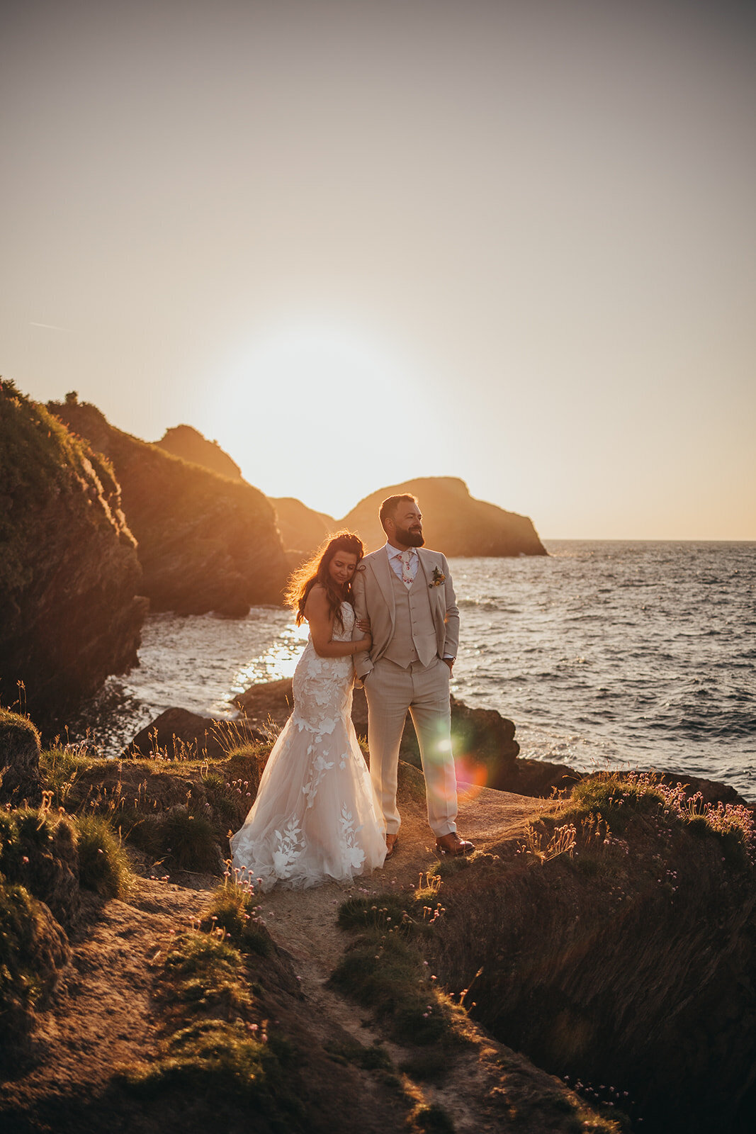 Couple stand on rocks by the ocean