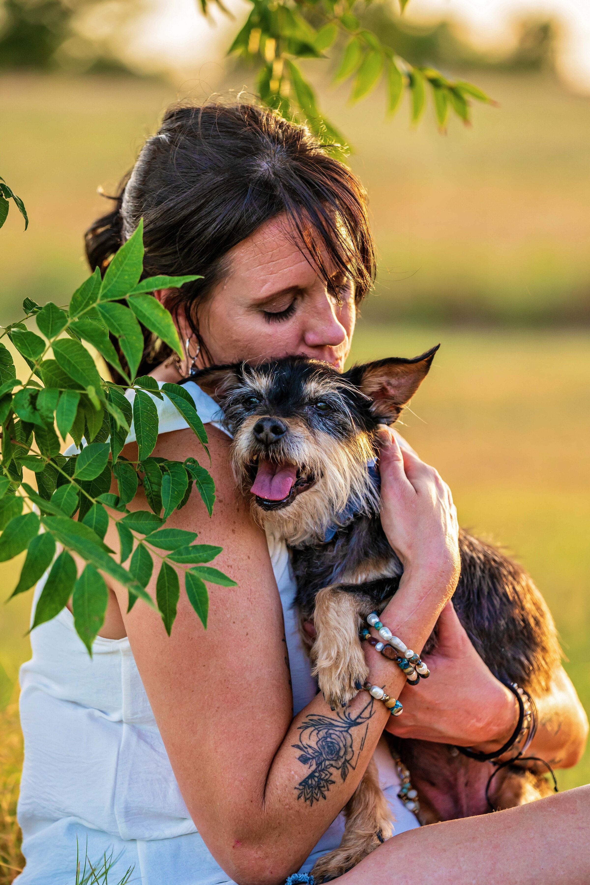 woman snuggling her dog under a tree
