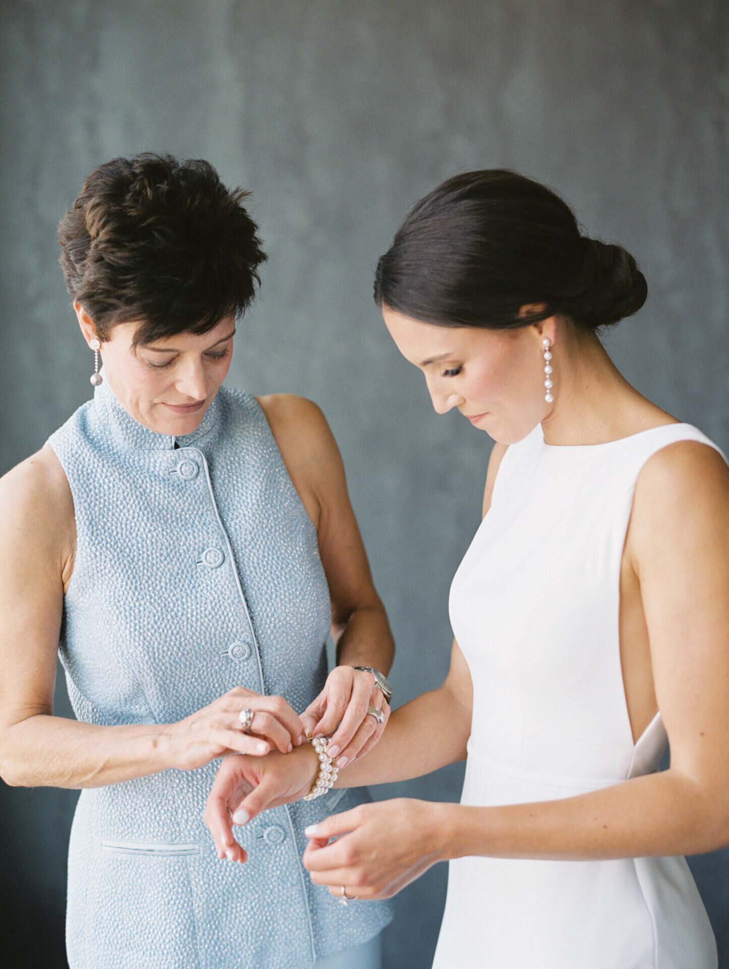 brides mother putting a pearl bracelet on her