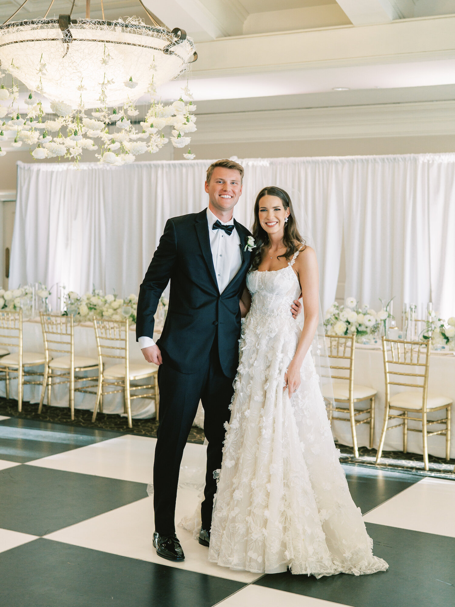 checkered ballroom floor with bride and groom smiling at camera