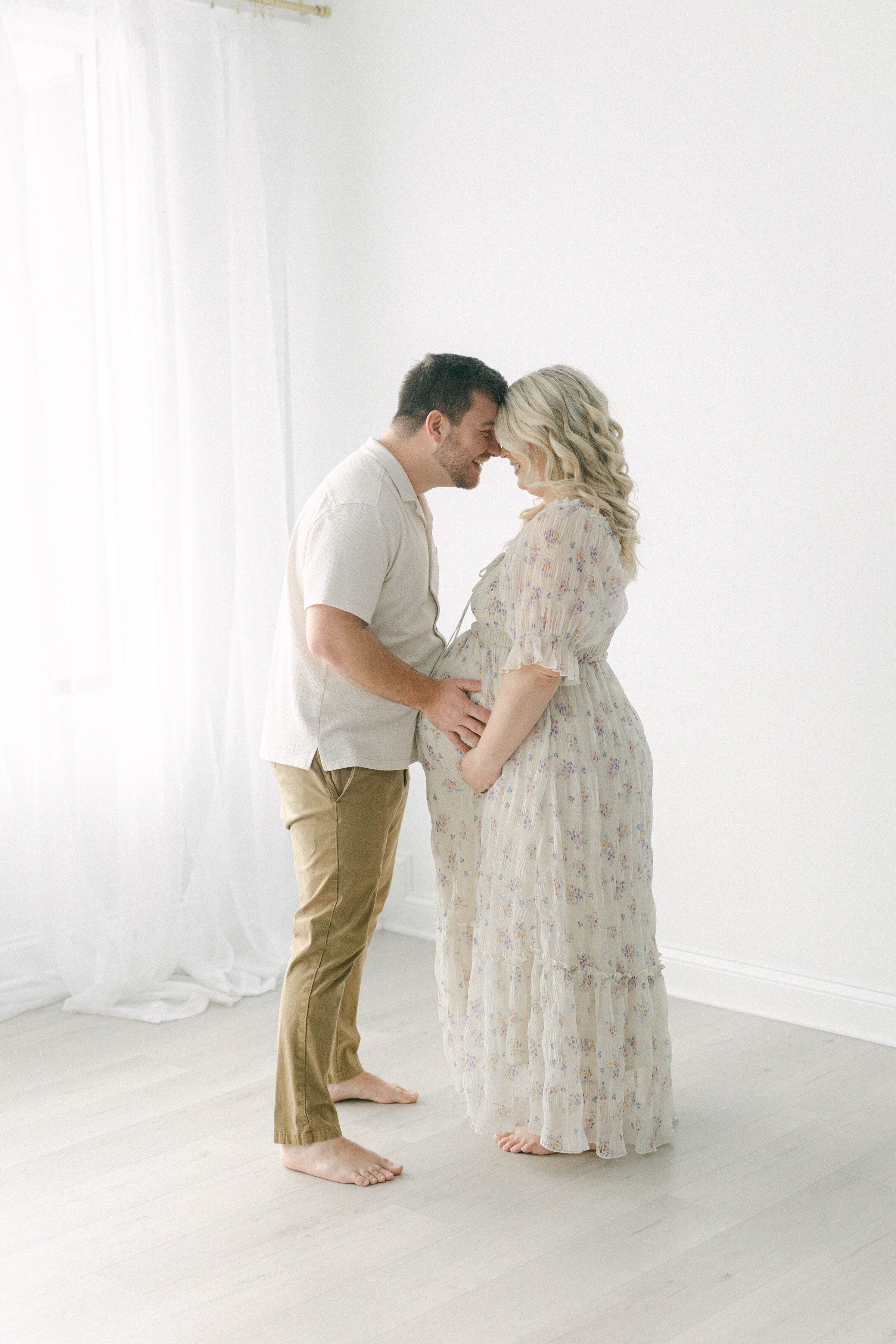 man and women standing forehead to forehead man holding women's pregnant belly both smiling knoxville tennessee newborn photographer