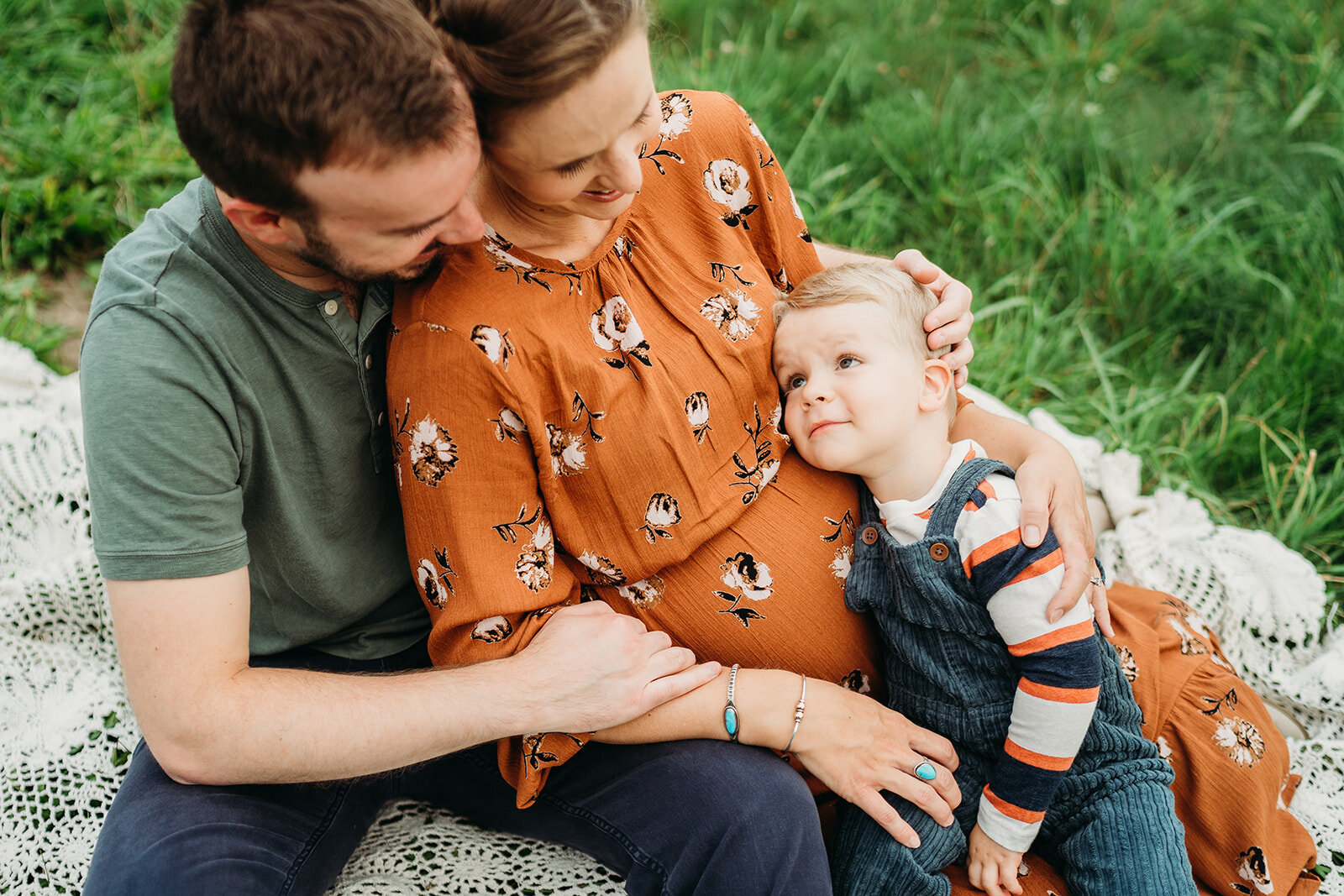 toddler big brother snuggles pregnant moms belly during family photos