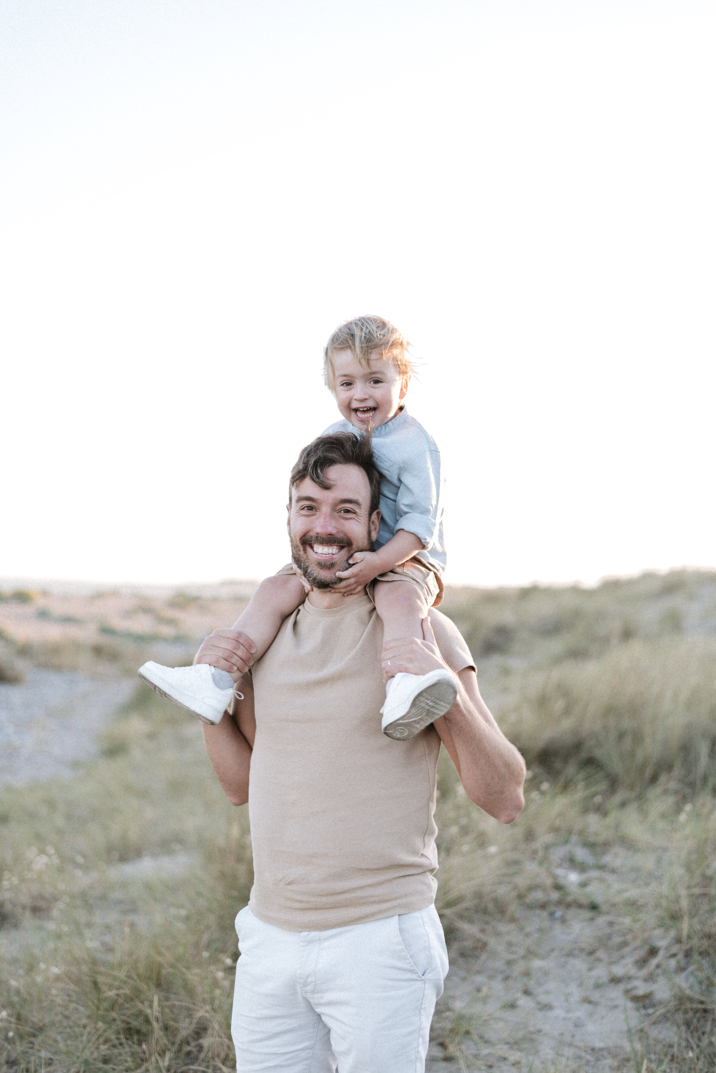 A dad with his son on his shoulders at family photography session in Billingshurst