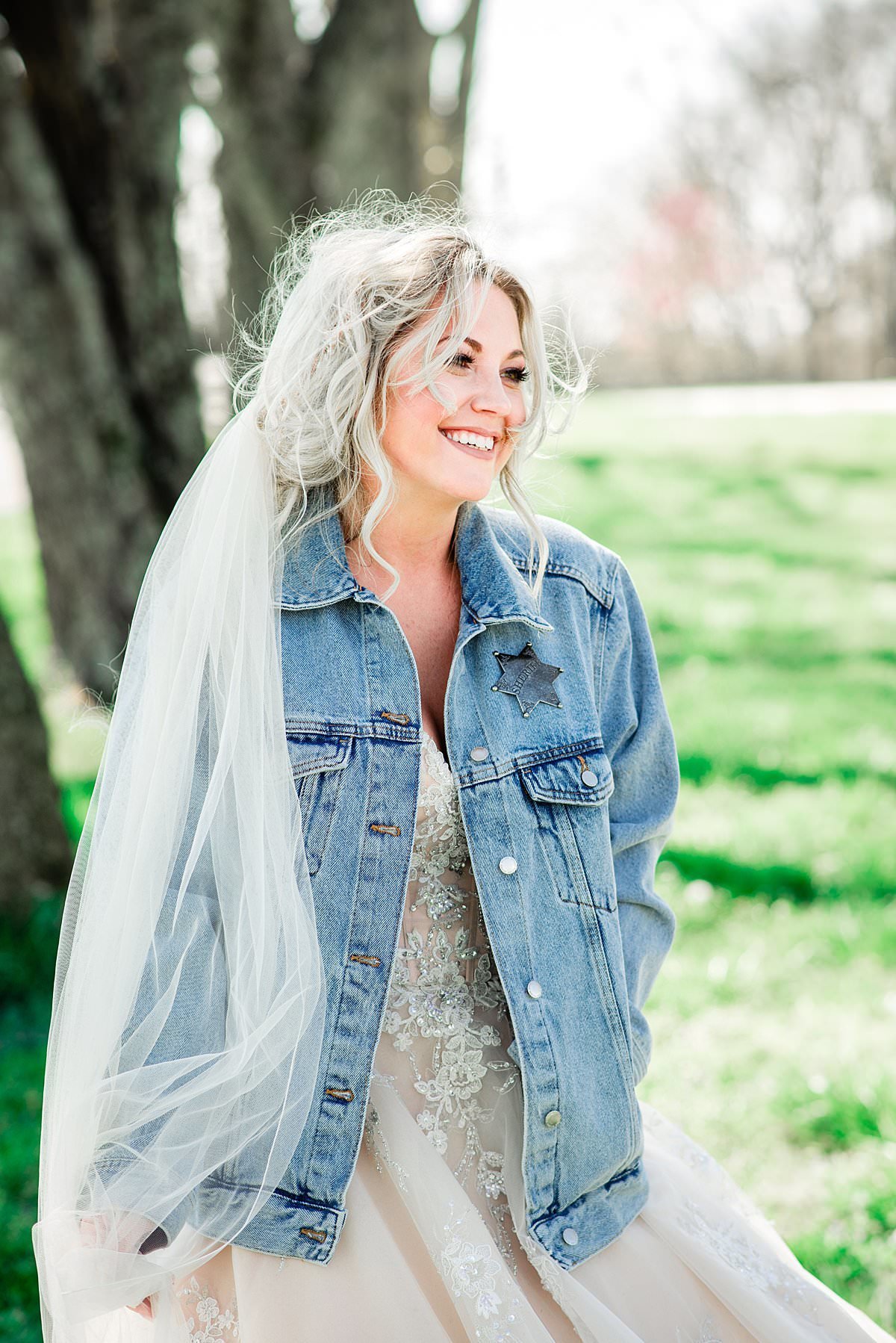 Bride wearing jean jacket paired with her wedding veil and large ballgown