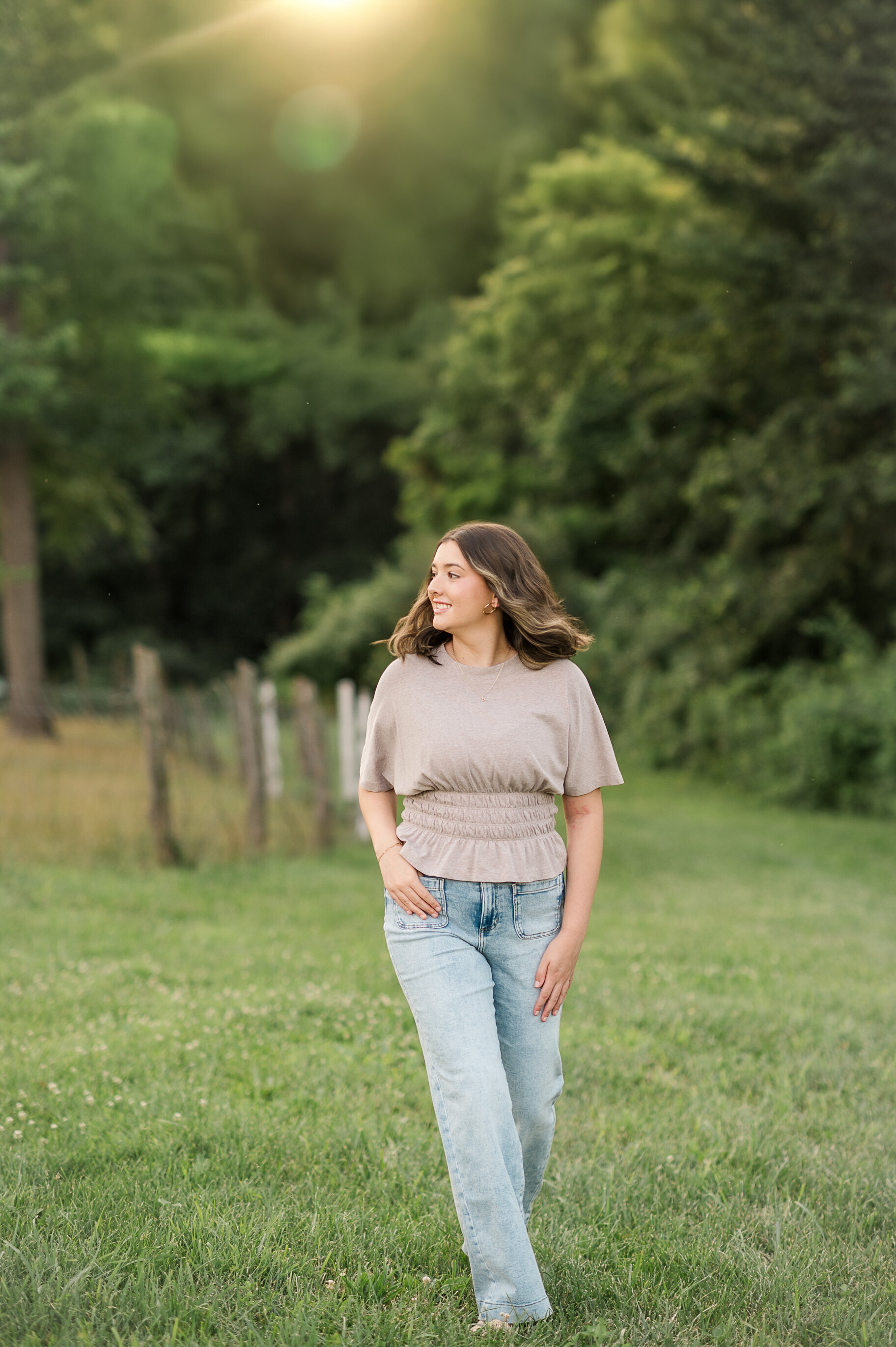 Senior girl in a field wearing jeans and a cropped top at John Rudy Park