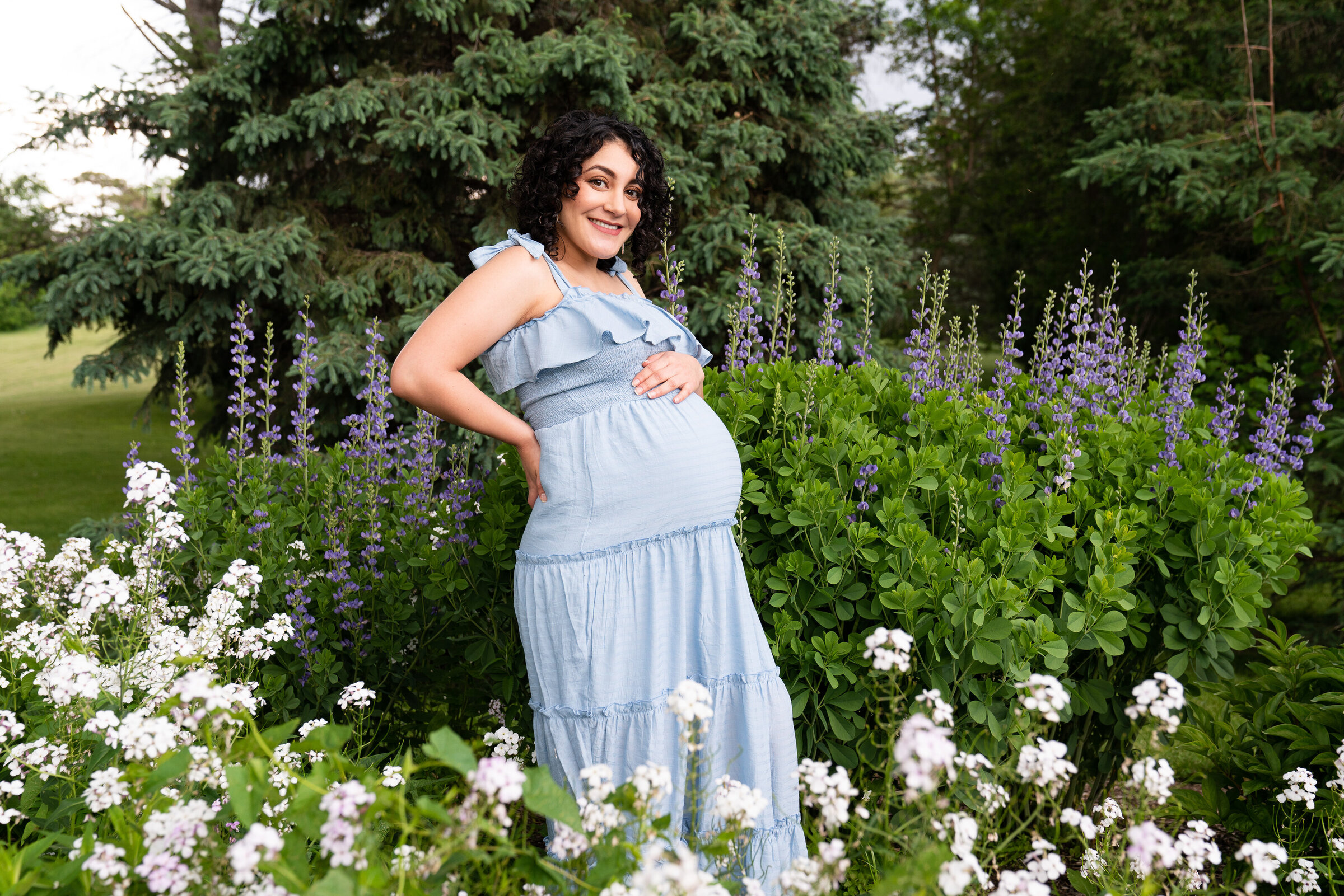 Woman posed in the flowers holding her baby bump