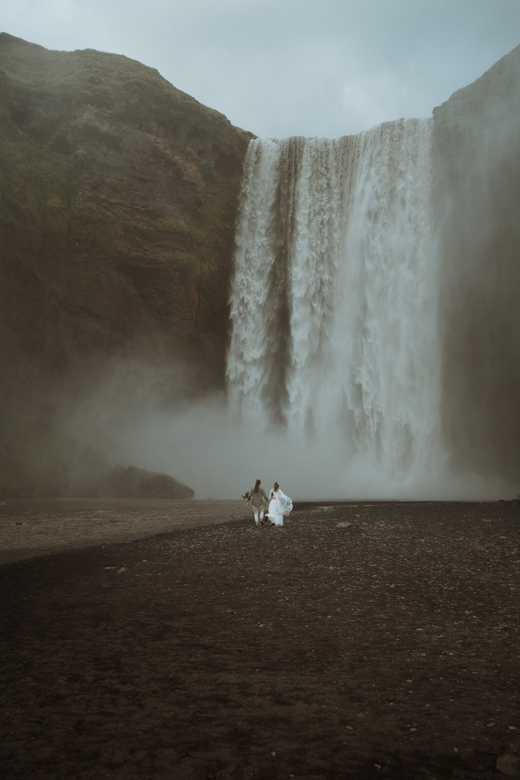 bride and groom standing in front of lake