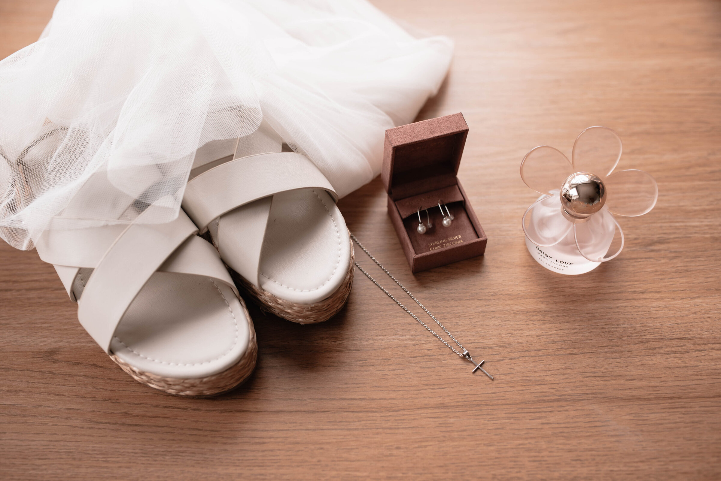Bridal shoes with veil, jewellery and perfume on a wooden table