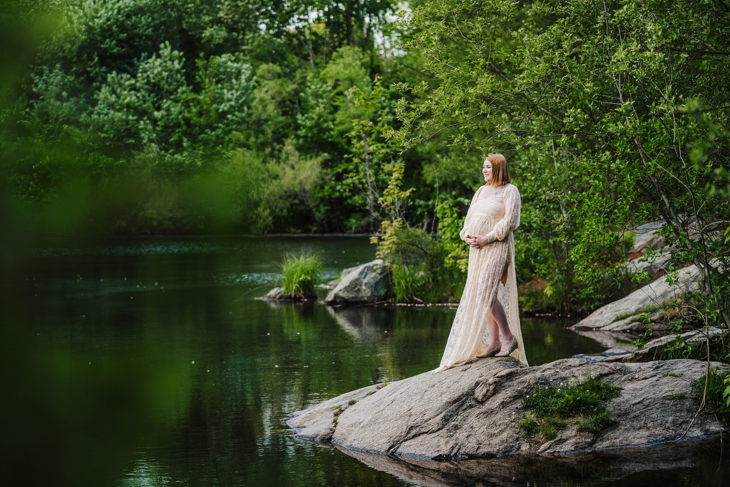 pregnant woman in pink dress stands in green backdrop