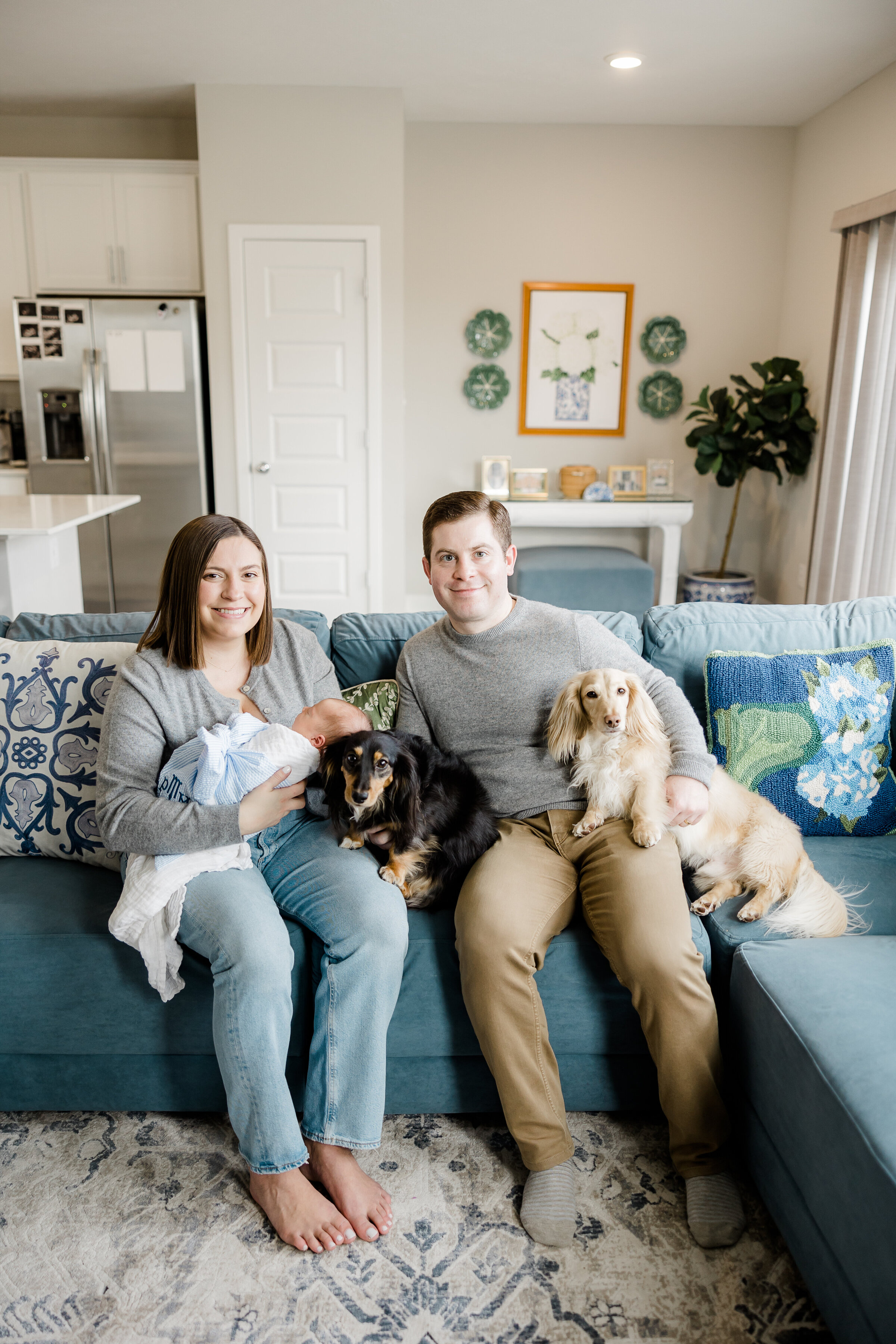 family photo sitting on couch with newborn and two dogs