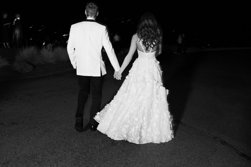 bride and groom holding hands at night walking away
