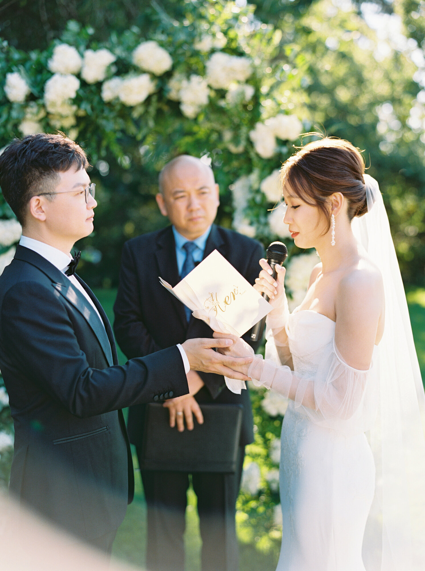 bride and groom reading vows to each other in garden ceremony