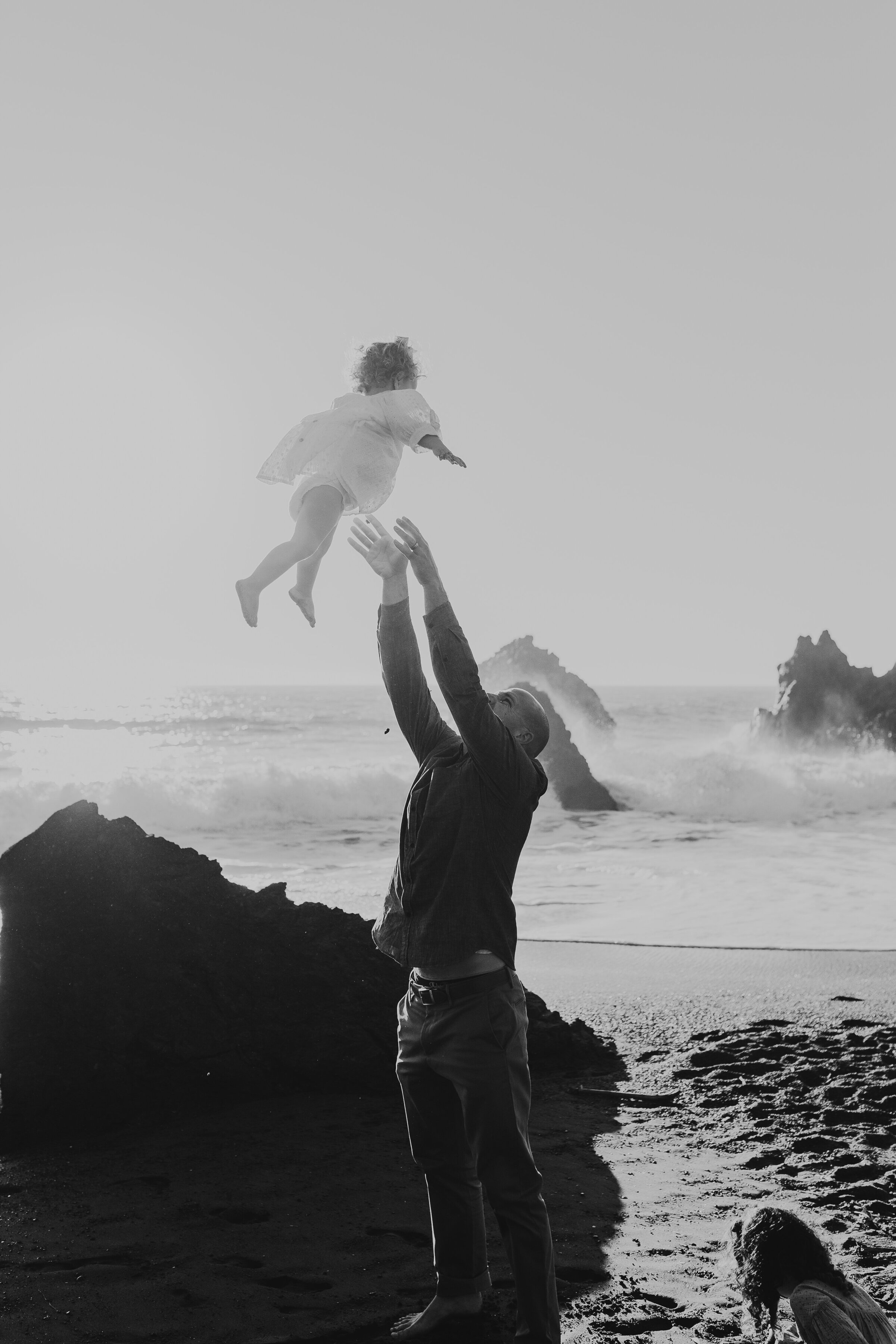 Dad throws his daughter up in the air on Rodeo Beach