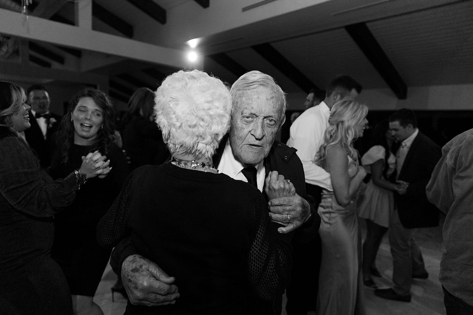 A grandma and grandpa dance together at their granddaughters wedding.