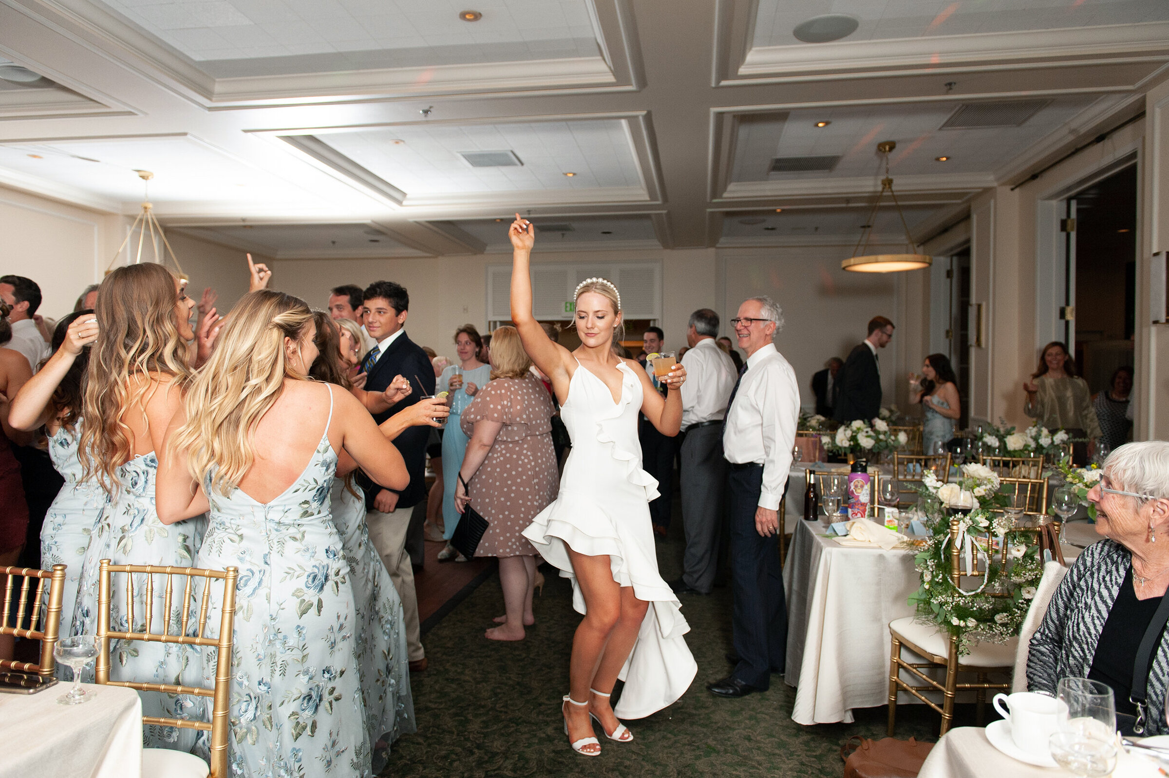 bride showing off her dress change to a short white reception dress and pearl headband