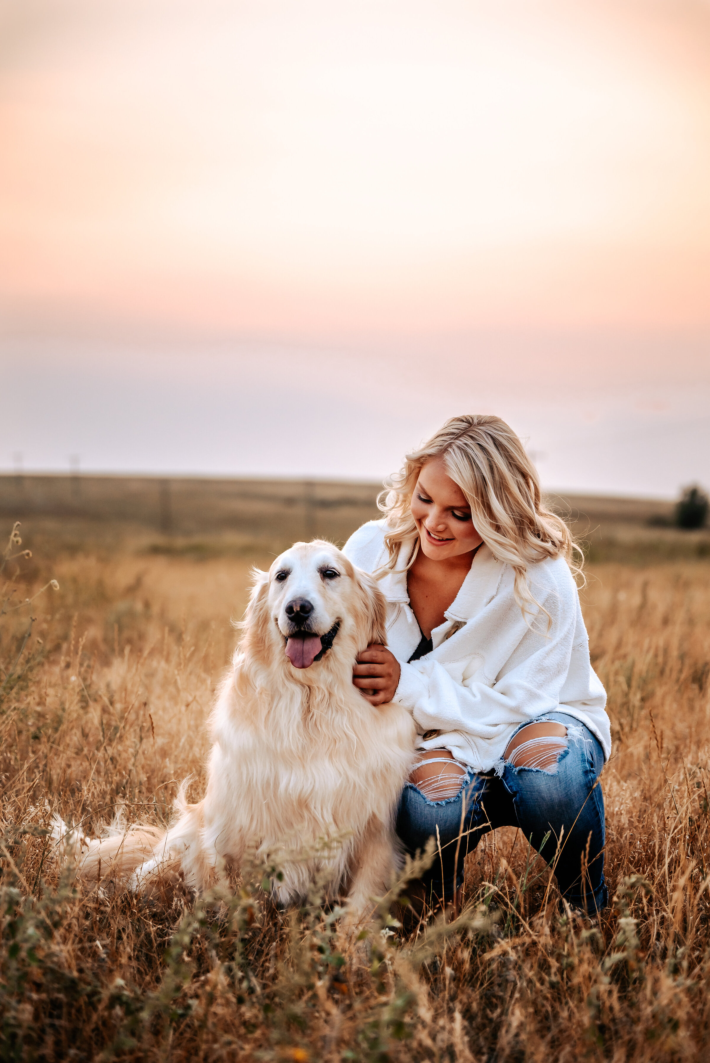 Senior girl pets her golden retriever dog in cattle field