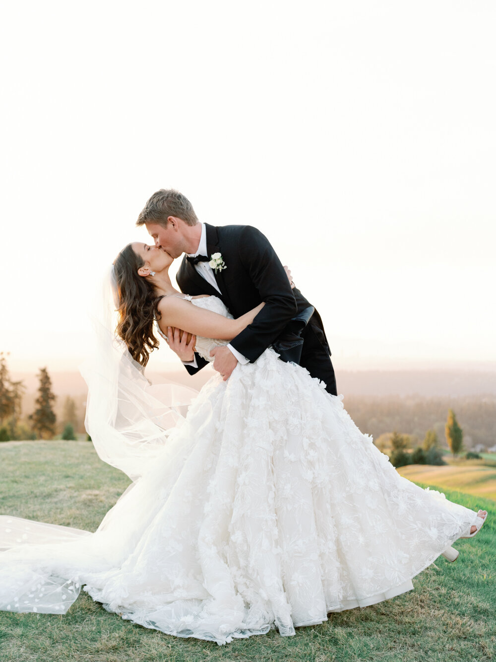 groom dipping and kissing bride outside at sunset