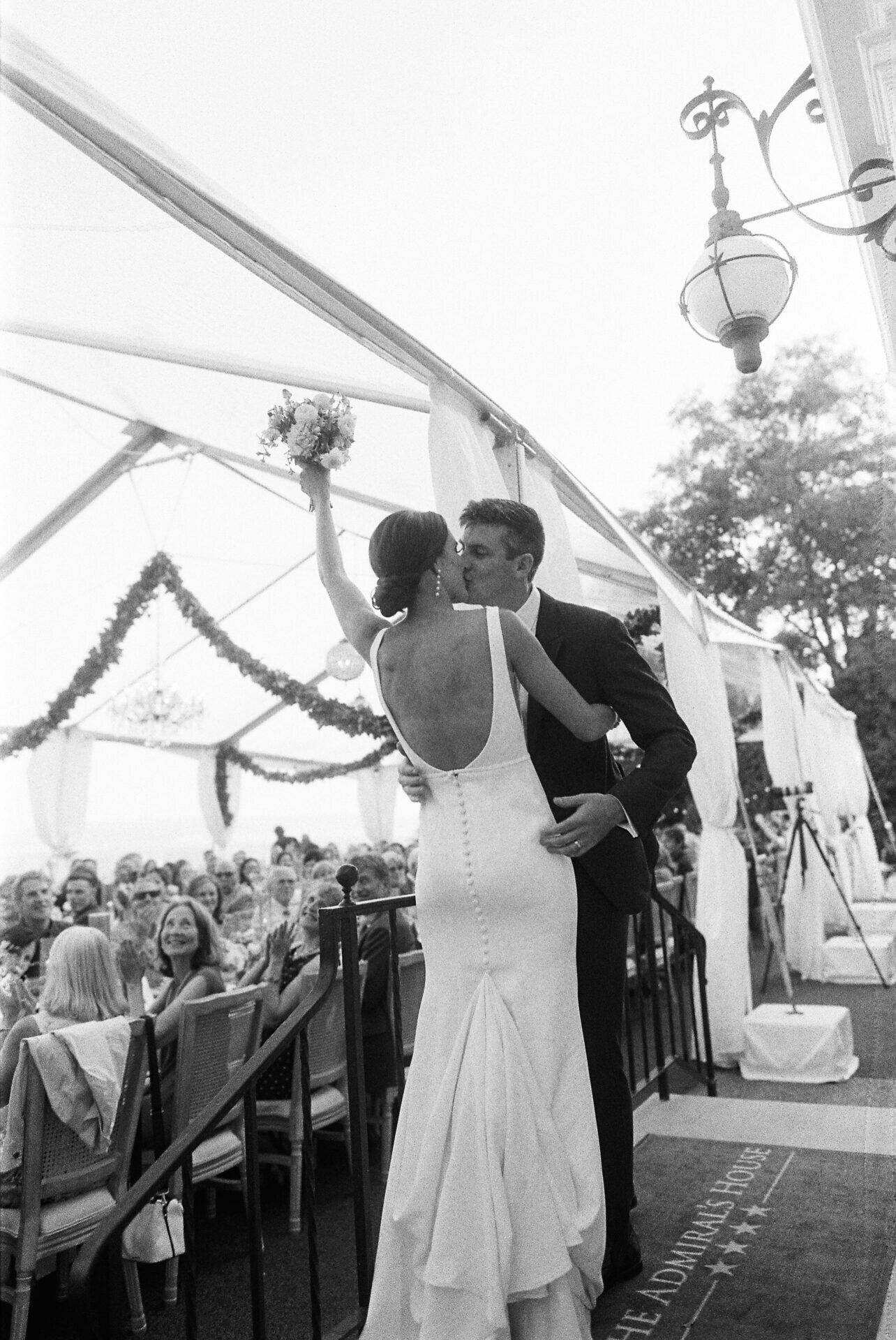 35 mm black and white photo of bride and groom kissing during grand entrance to reception