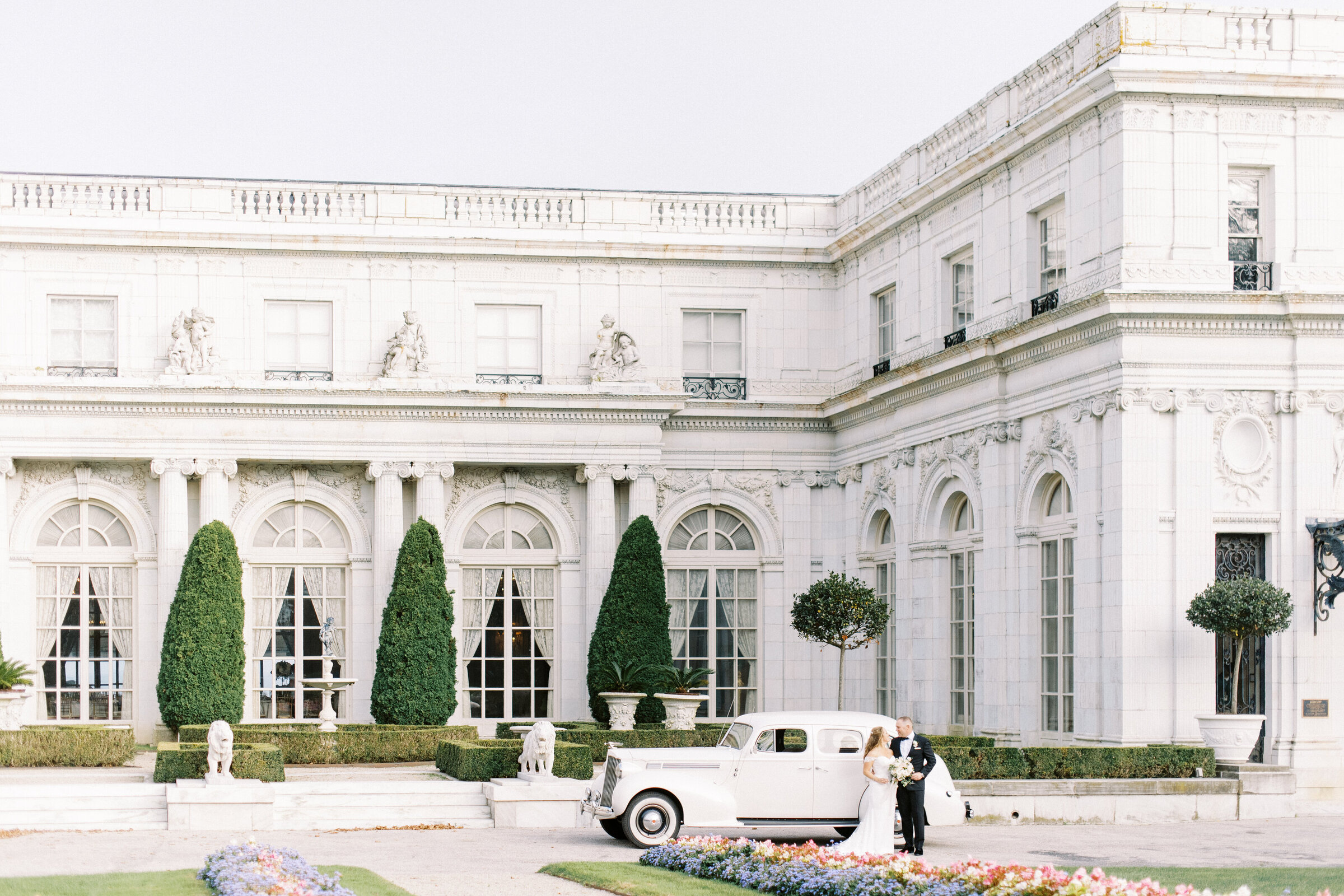 wedding portrait of bride and groom in Newport RI in front of Rosecliff mansion with a classic car