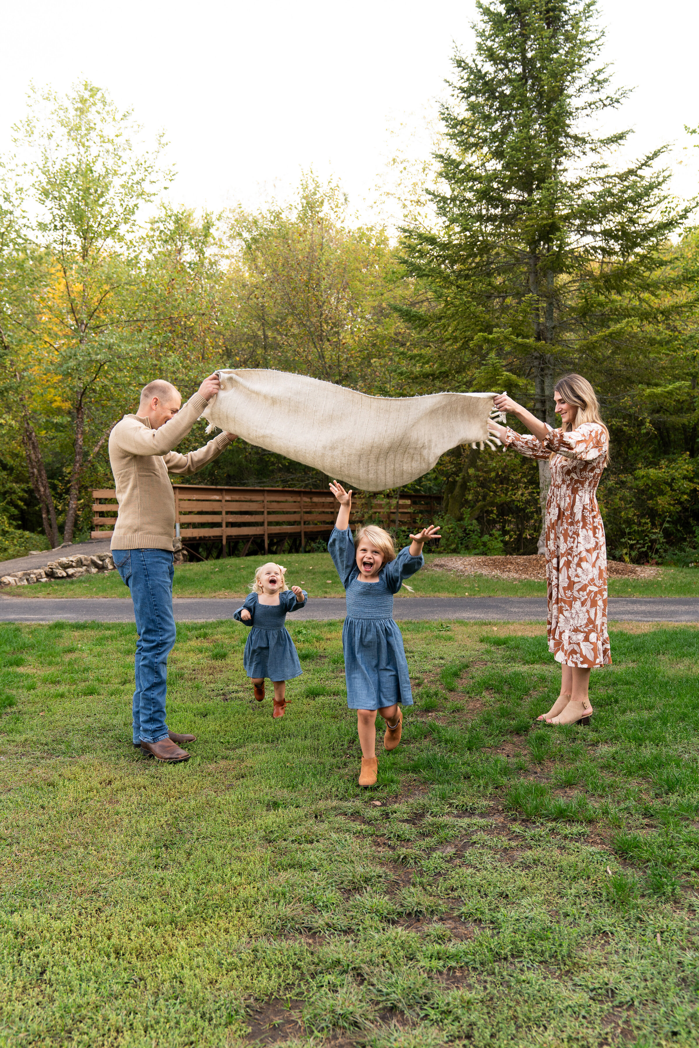 A mom and dad play with their daughters during their family pictures.