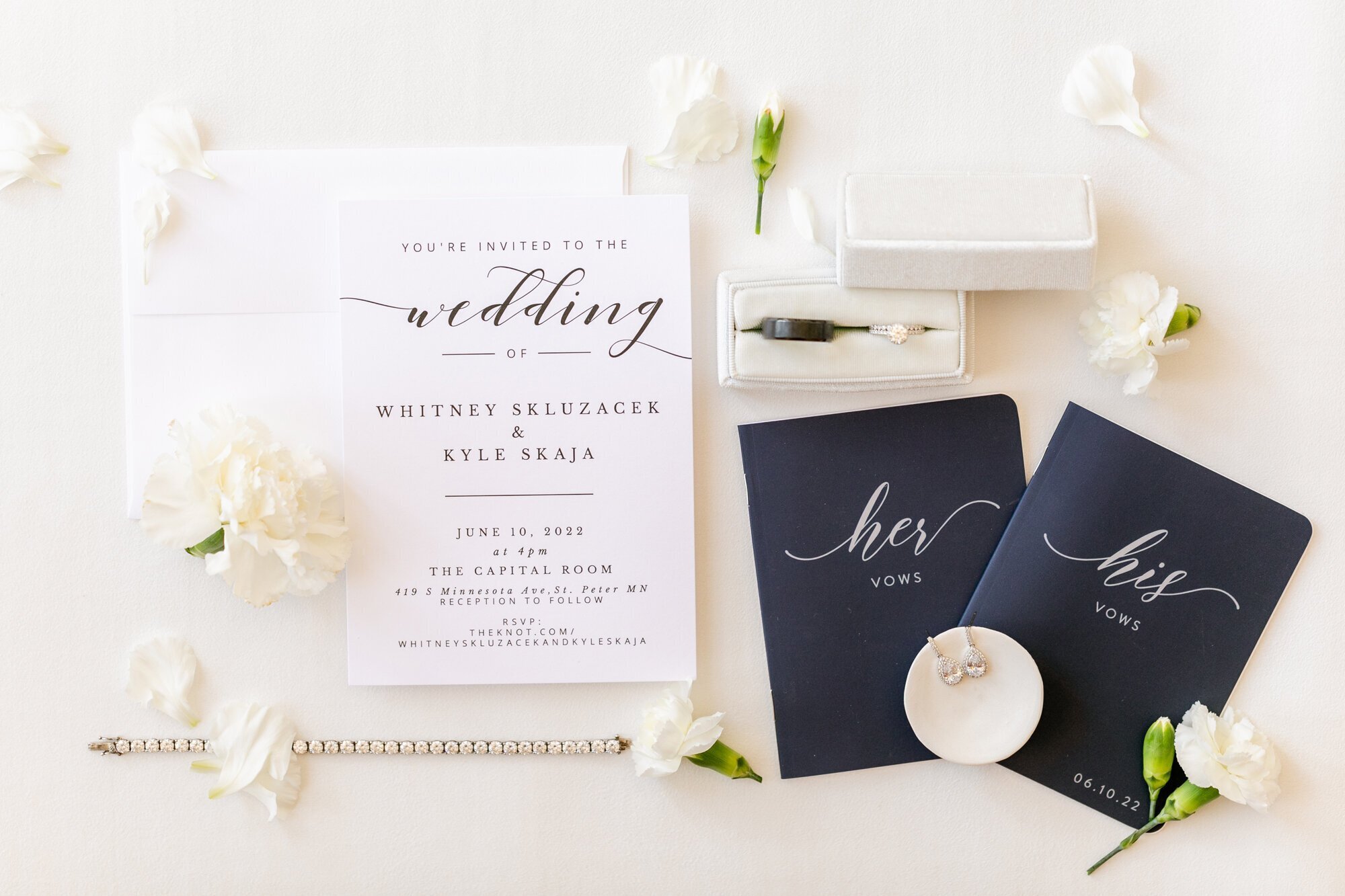 Wedding details including invites, vow books, earrings, and rings, for a minnesota wedding