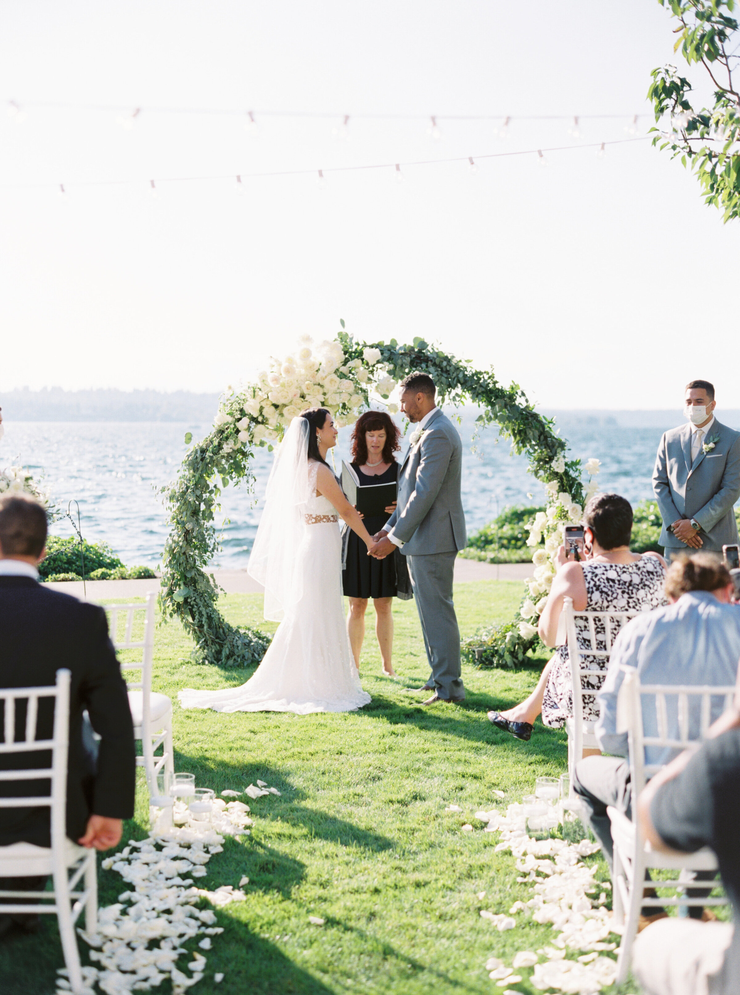 bride and groom face each other at outdoor sunny ceremony on grass