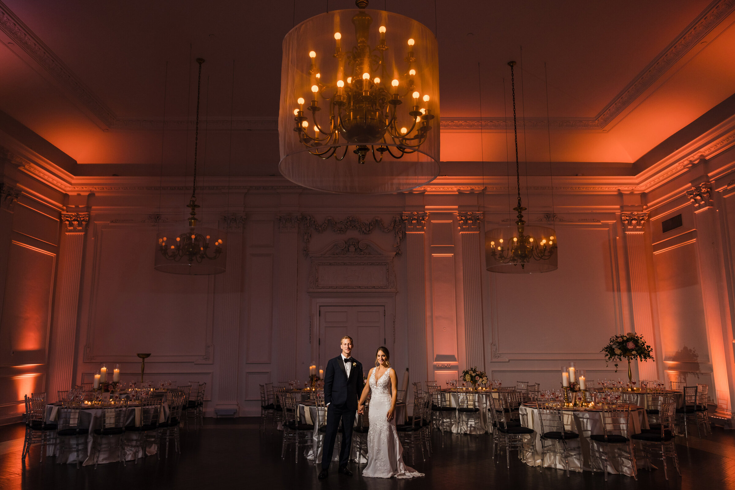 Wide angle of the Down Town Club ballroom with bride and groom standing in the middle holding hands captured by Anastasia Romanova
