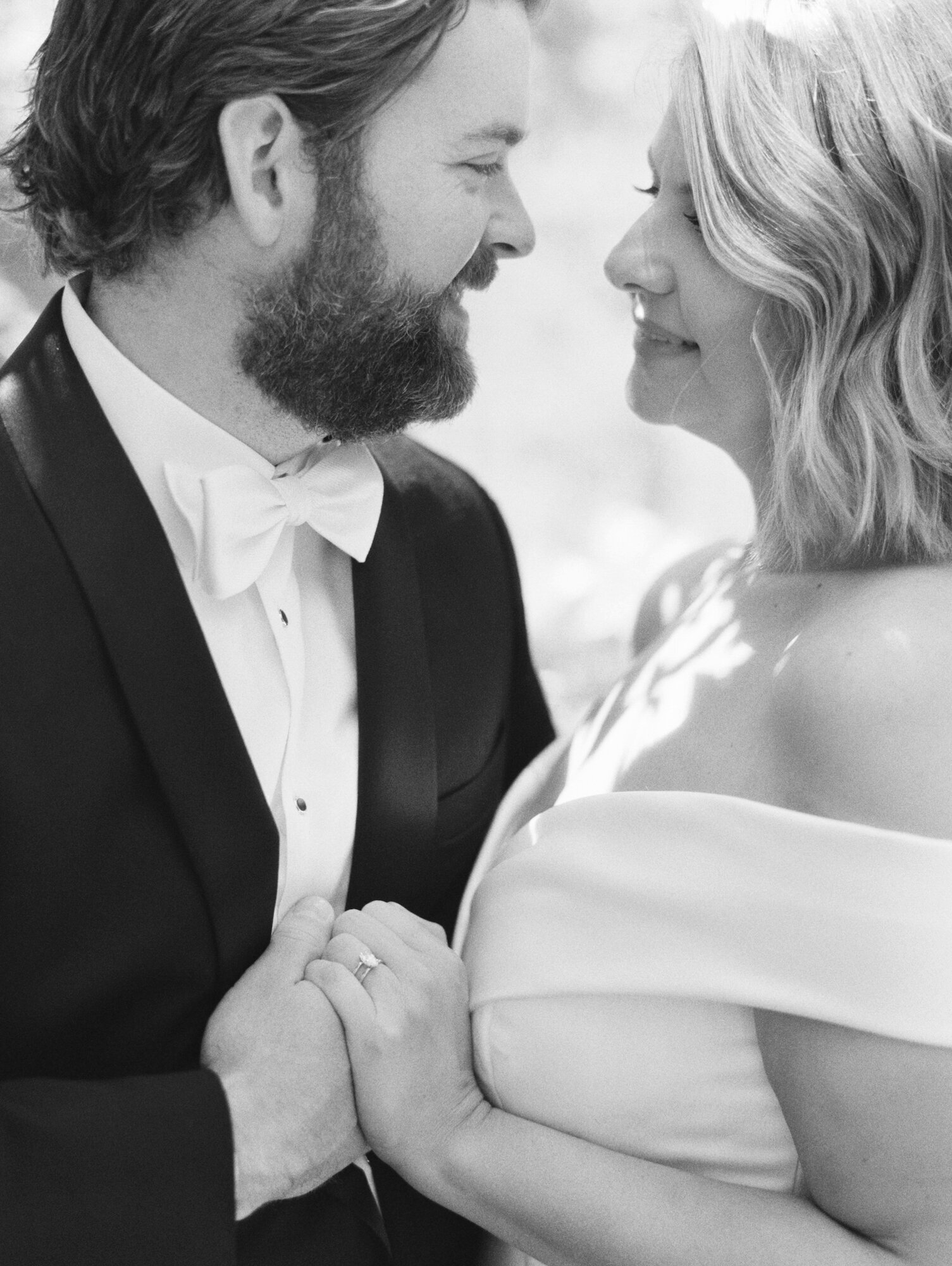 classic black and white film photo of a groom holding brides hand up close