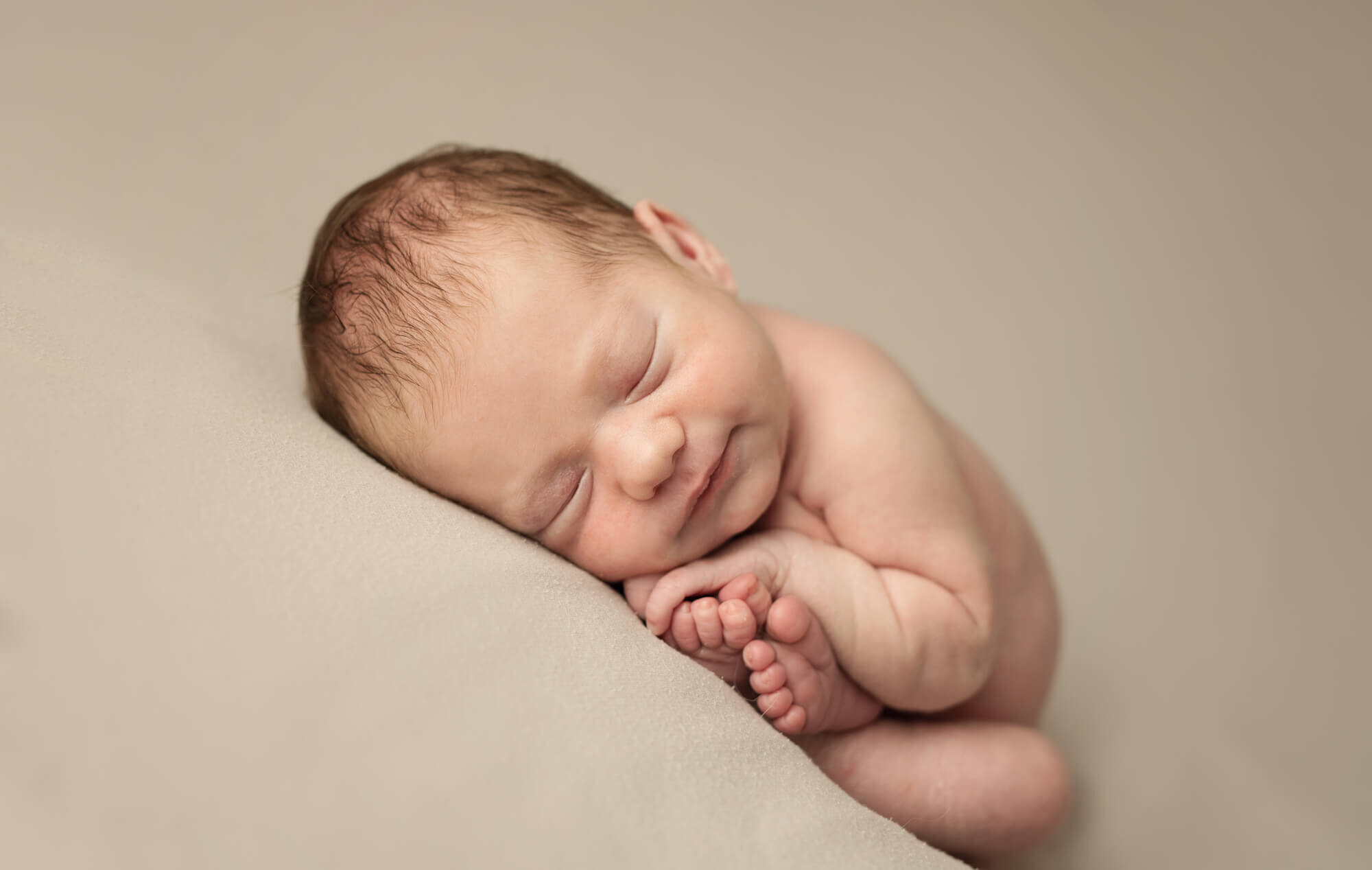 Sleeping newborn boy in taco pose