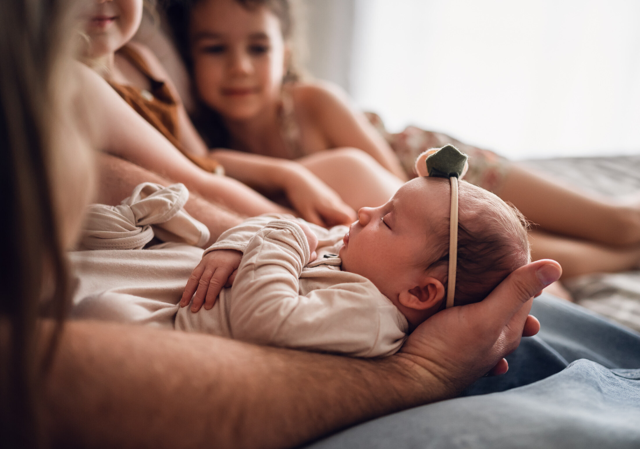 Family snuggling baby on a bed