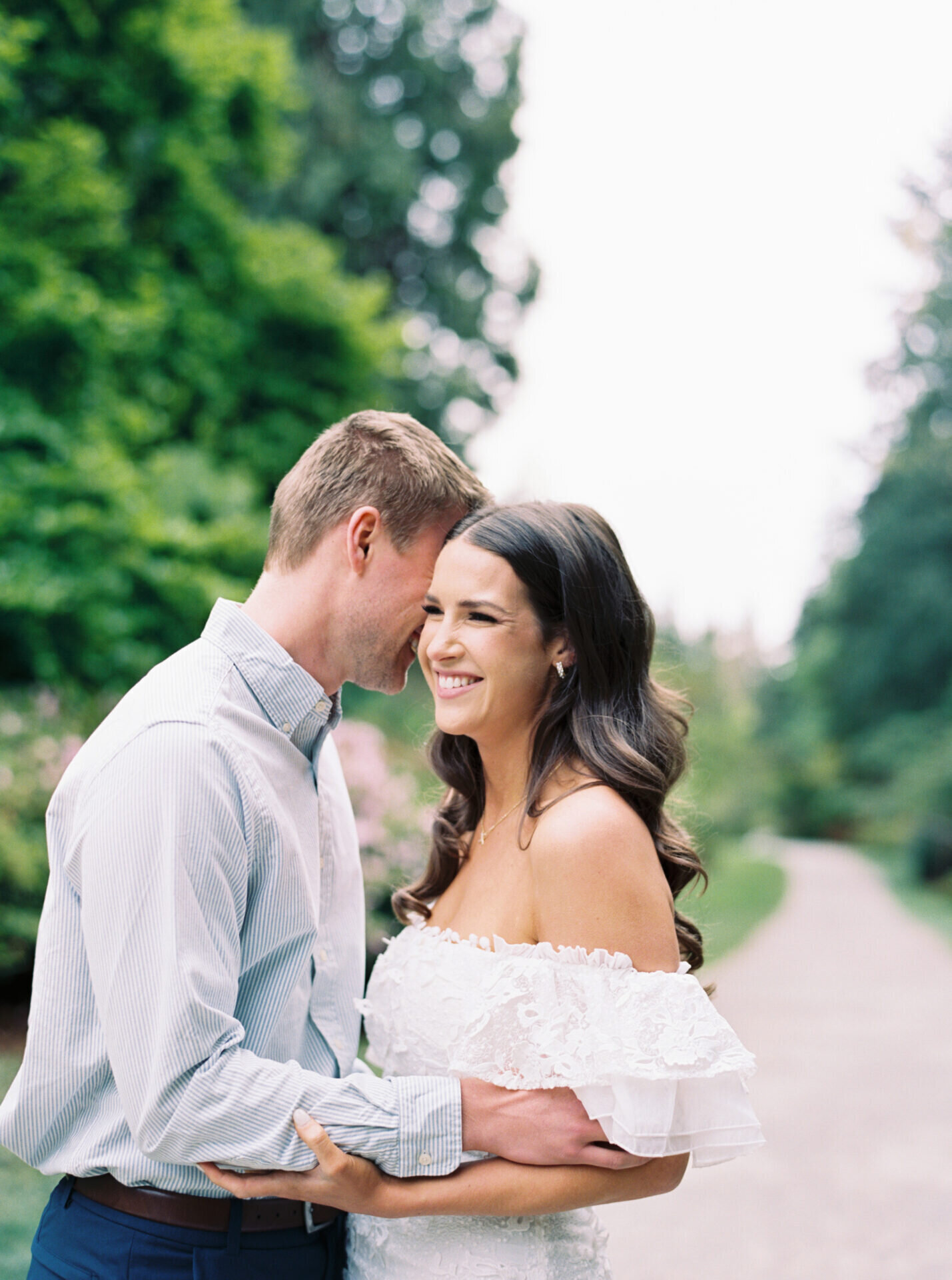 smiling couple cuddles in white dress and blue shirt