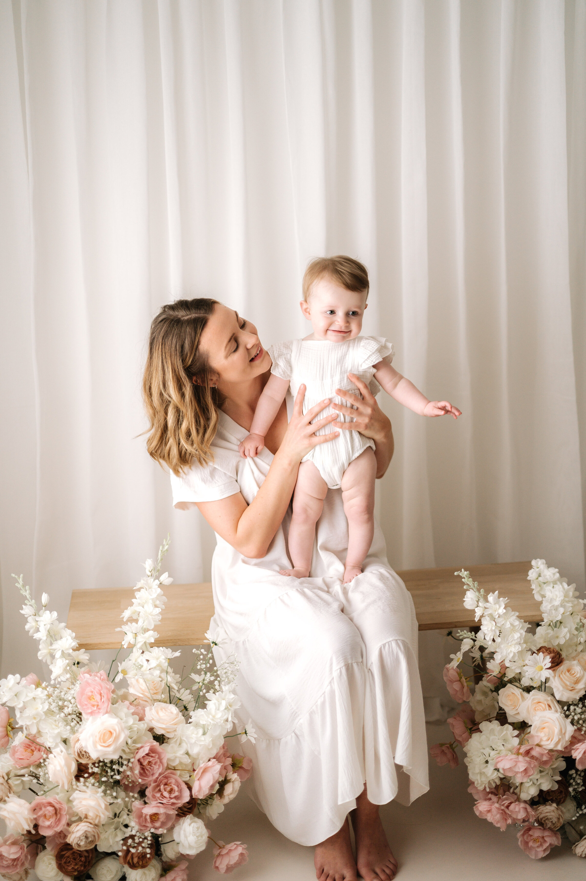 One year old girl standing up on her mums legs at a Horsham family photoshoot