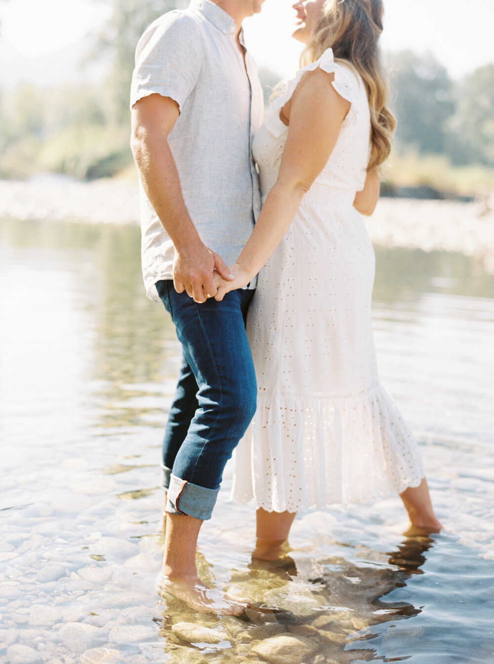 couple holding hands in river for engagement photos in north bend