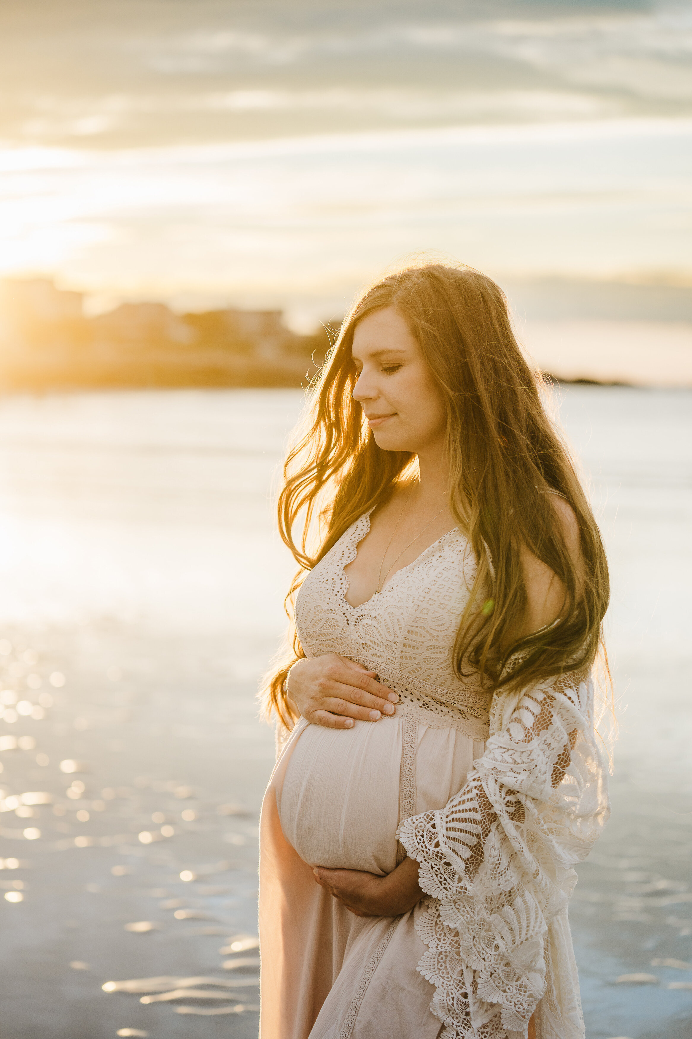 pregnant woman in lace shawl at sunset beach
