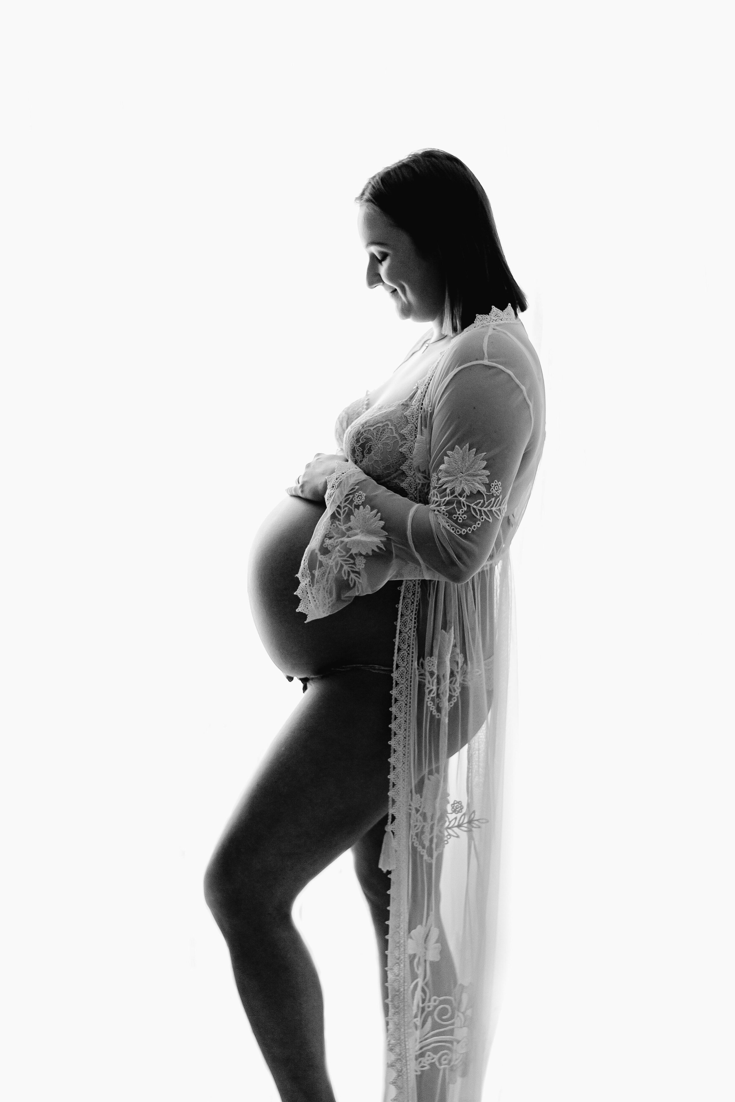 A expecting mother holding her belly at maternity photoshoot in Billingshurst