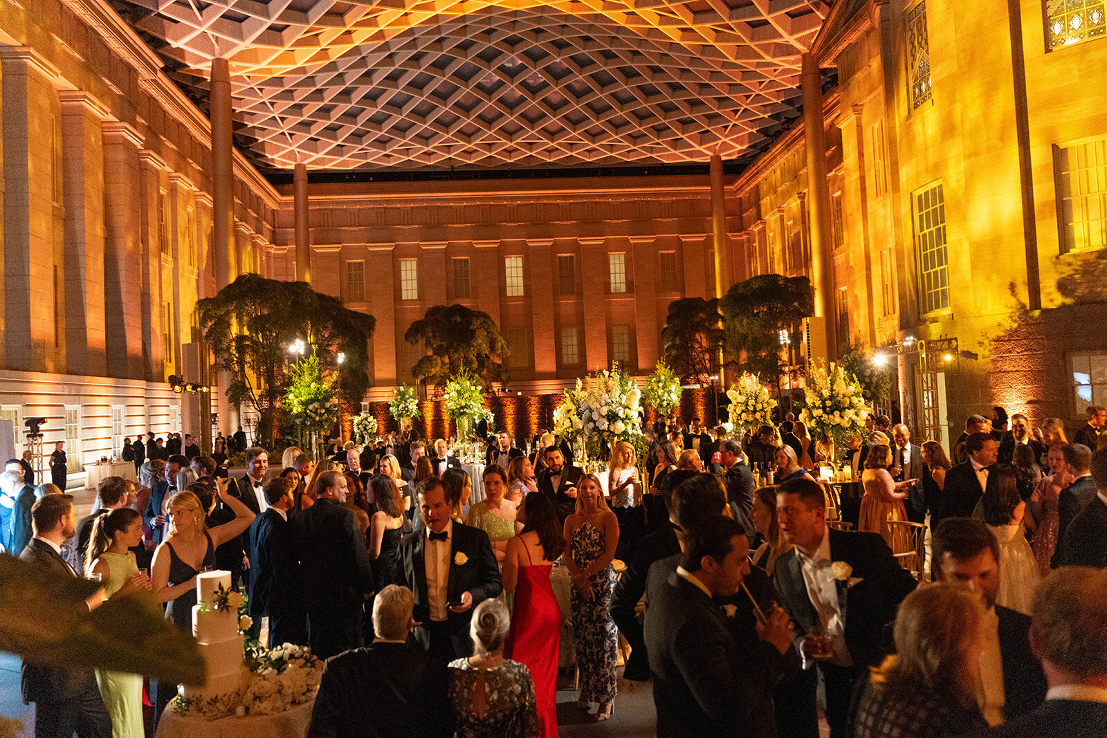 Elegant wedding reception under the glass canopy at the Smithsonian National Portrait Gallery in Washington DC, with guests dancing and celebrating, photographed by Mari Harsan Studios.
