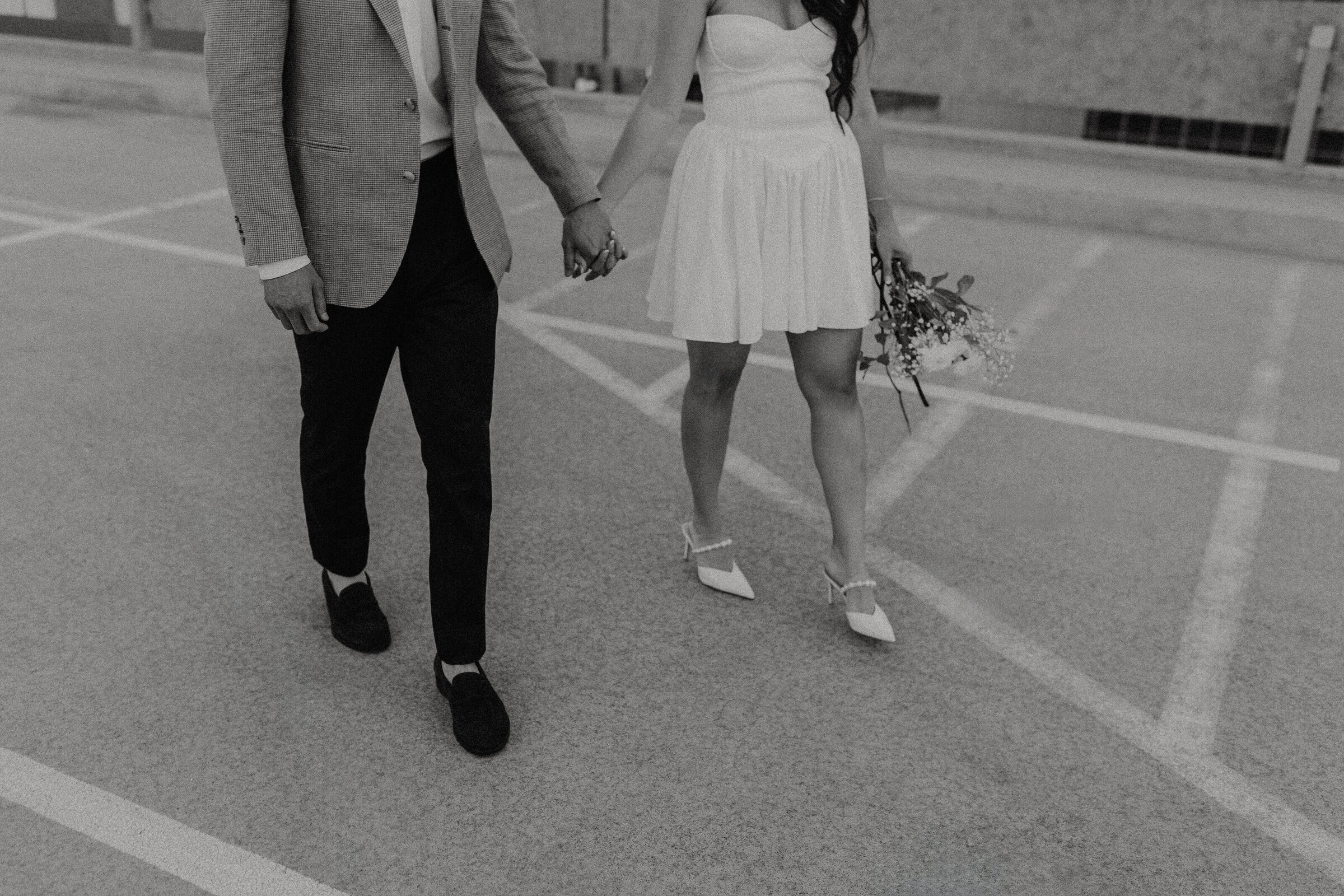 Black and white image of a man and a woman holding hands on a downtown phoenix parking garage rooftop