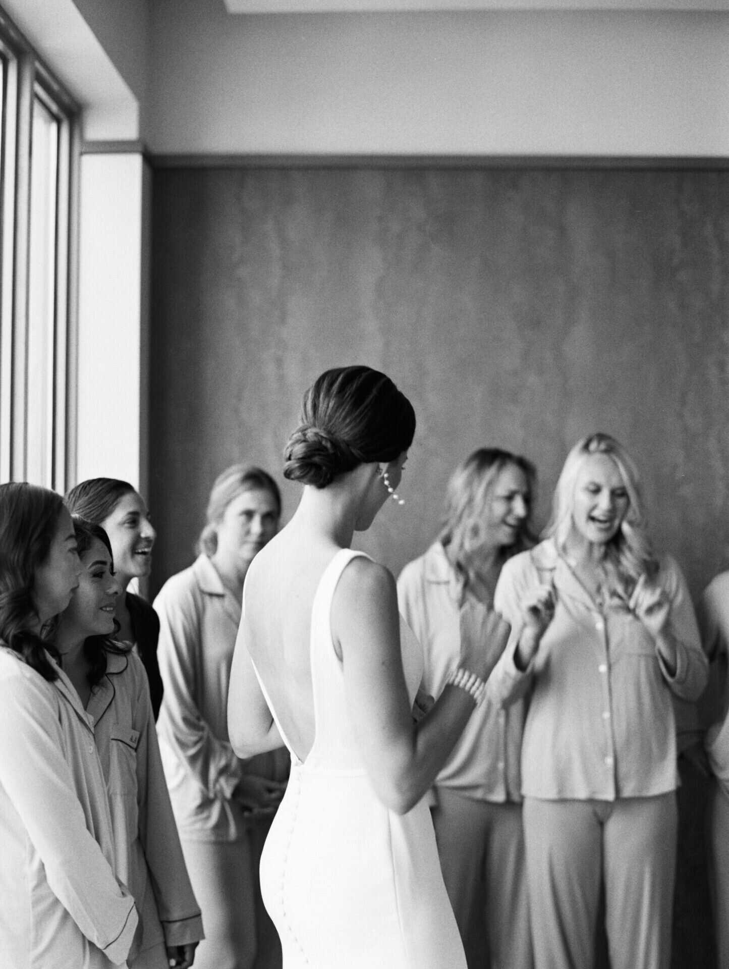 black and white photo of bride looking at her bridesmaids in a hotel room