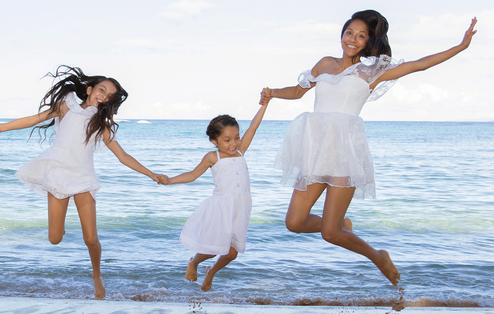 Two daughters and their mum jumping on the  sand, super happy photography session on Maui.