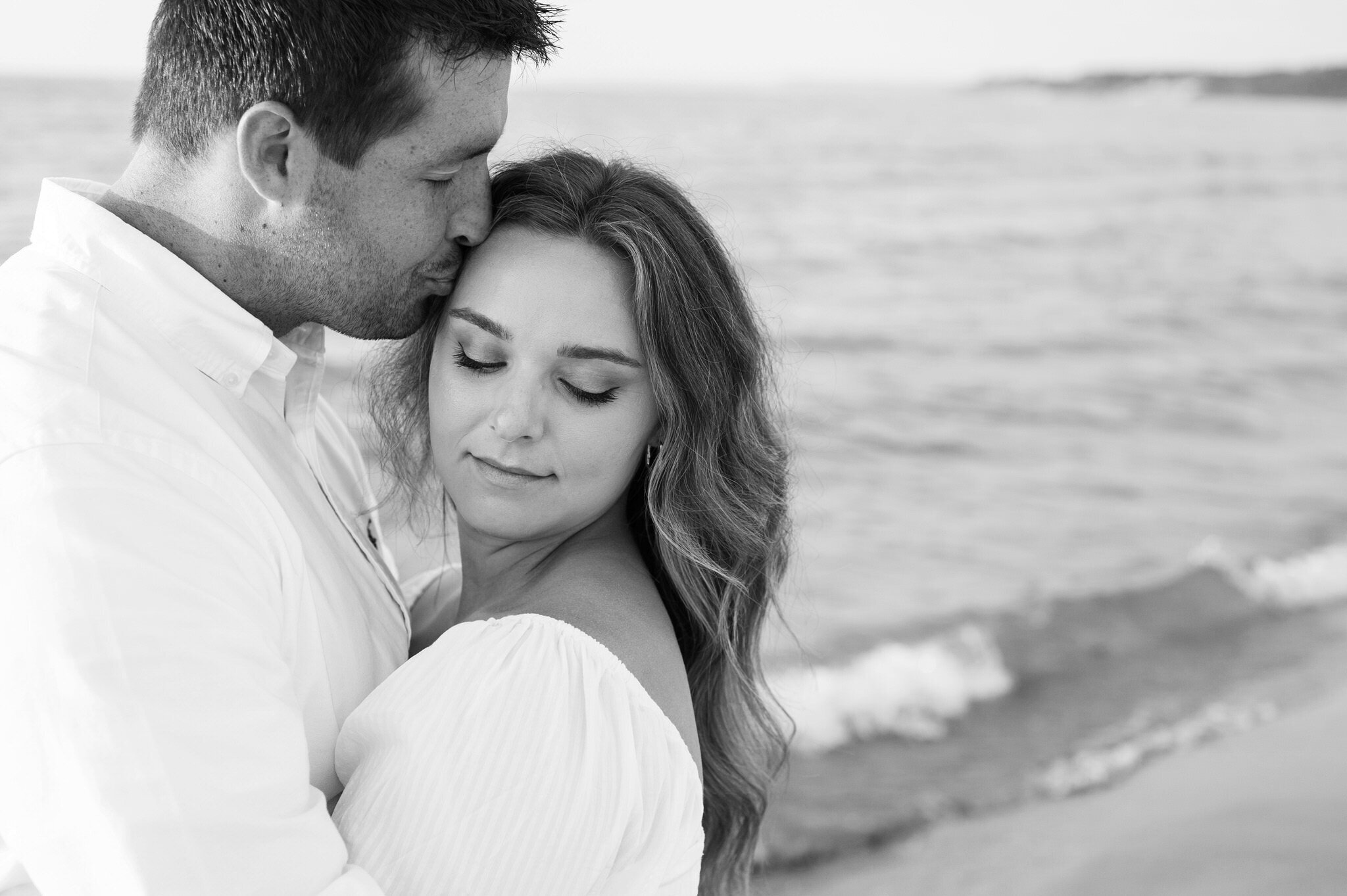 man kissing his fiances forehead on a Northern Michigan beach