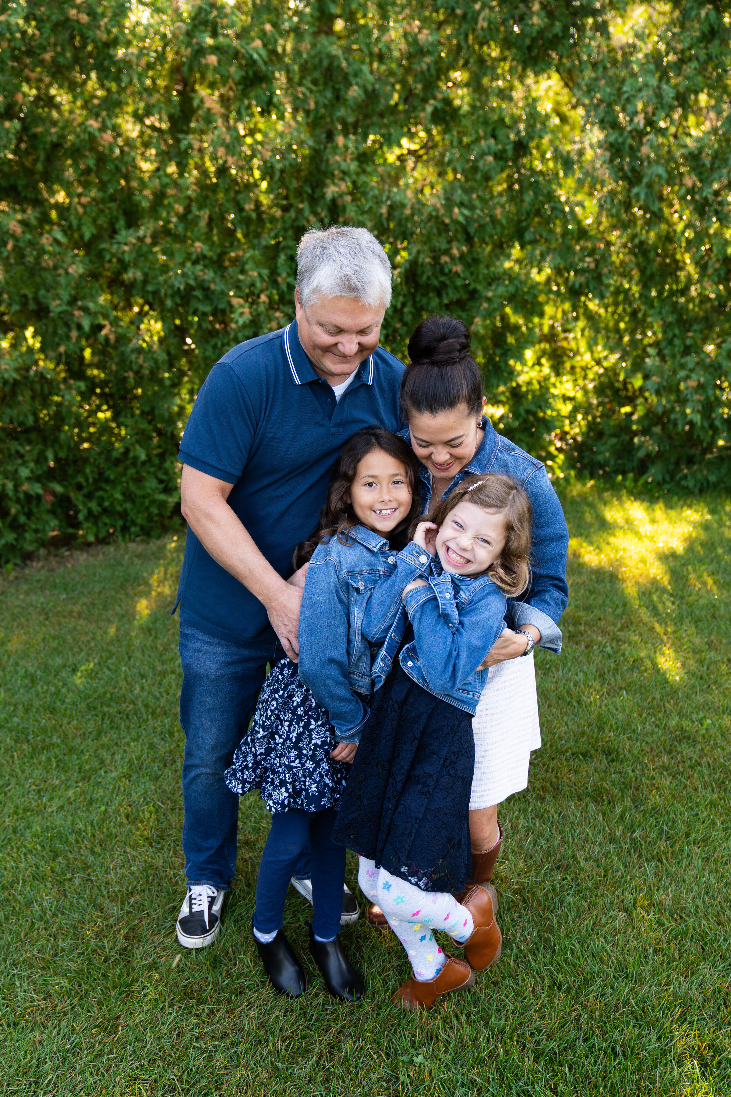 A mom and dad tickle their daughters during their family photo shoot.