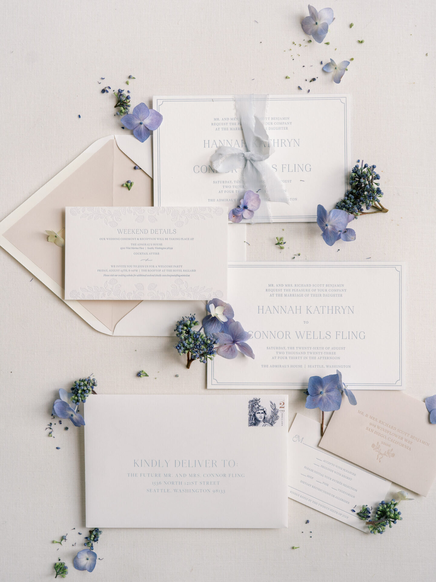 purple flowers surrounding wedding invitations flat lay design
