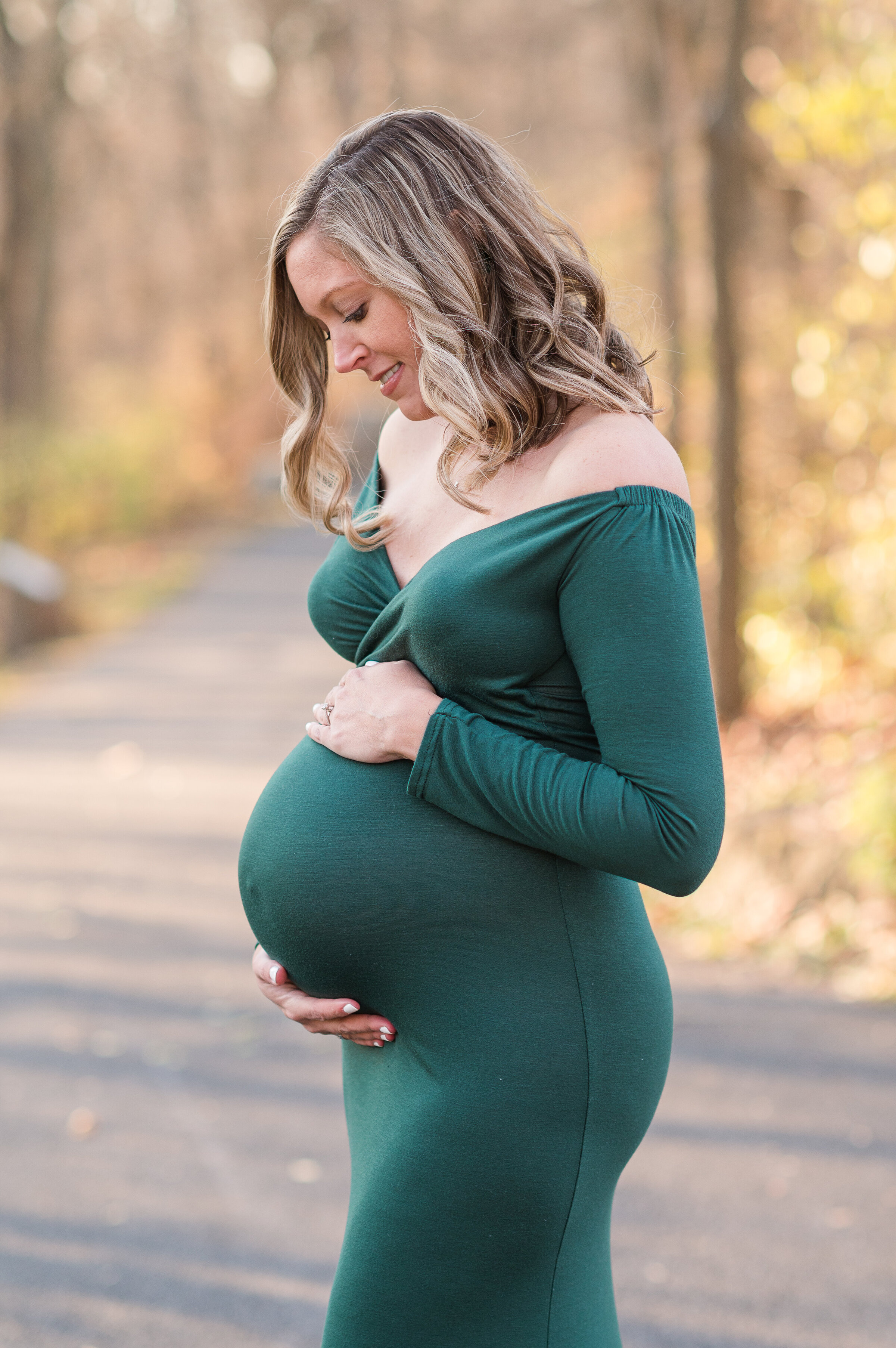 Maternity session in harrisburg pa with mother holding belly and smiling in a dark green dress