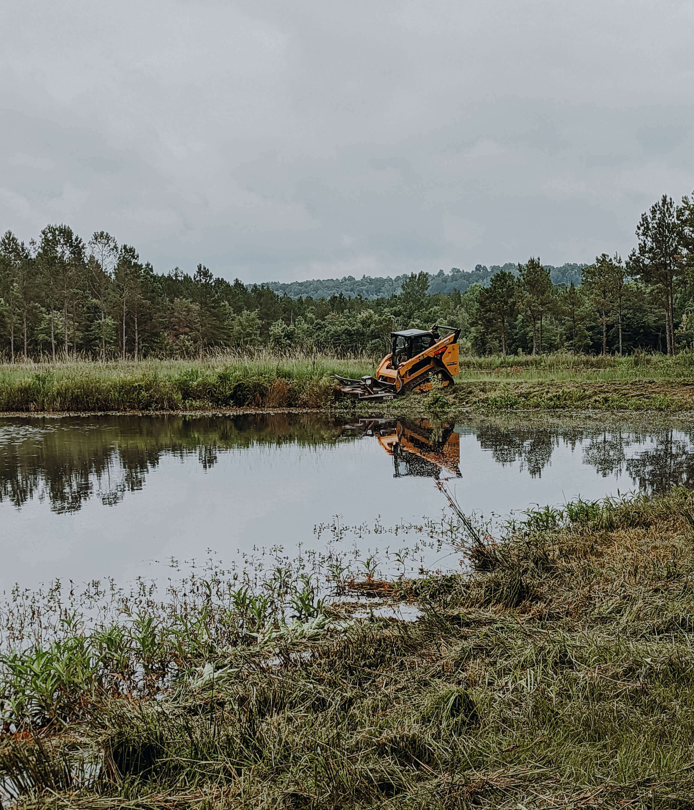 excavator-cleaning-edge-of-pond-on-a-cloudy-day