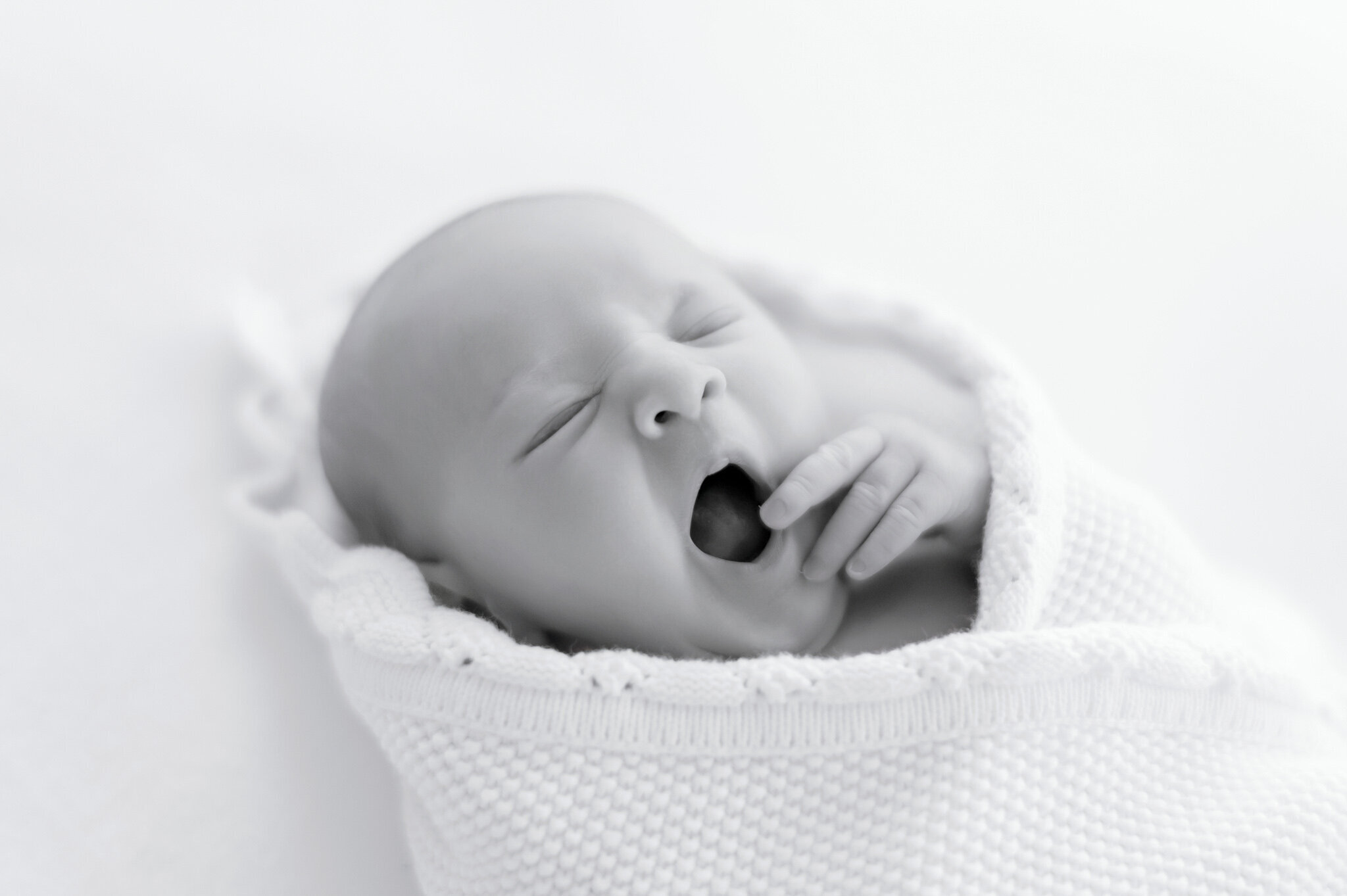 black and white image of a newborn yawning  in Kristie Lloyd's Nashville newborn photography studio