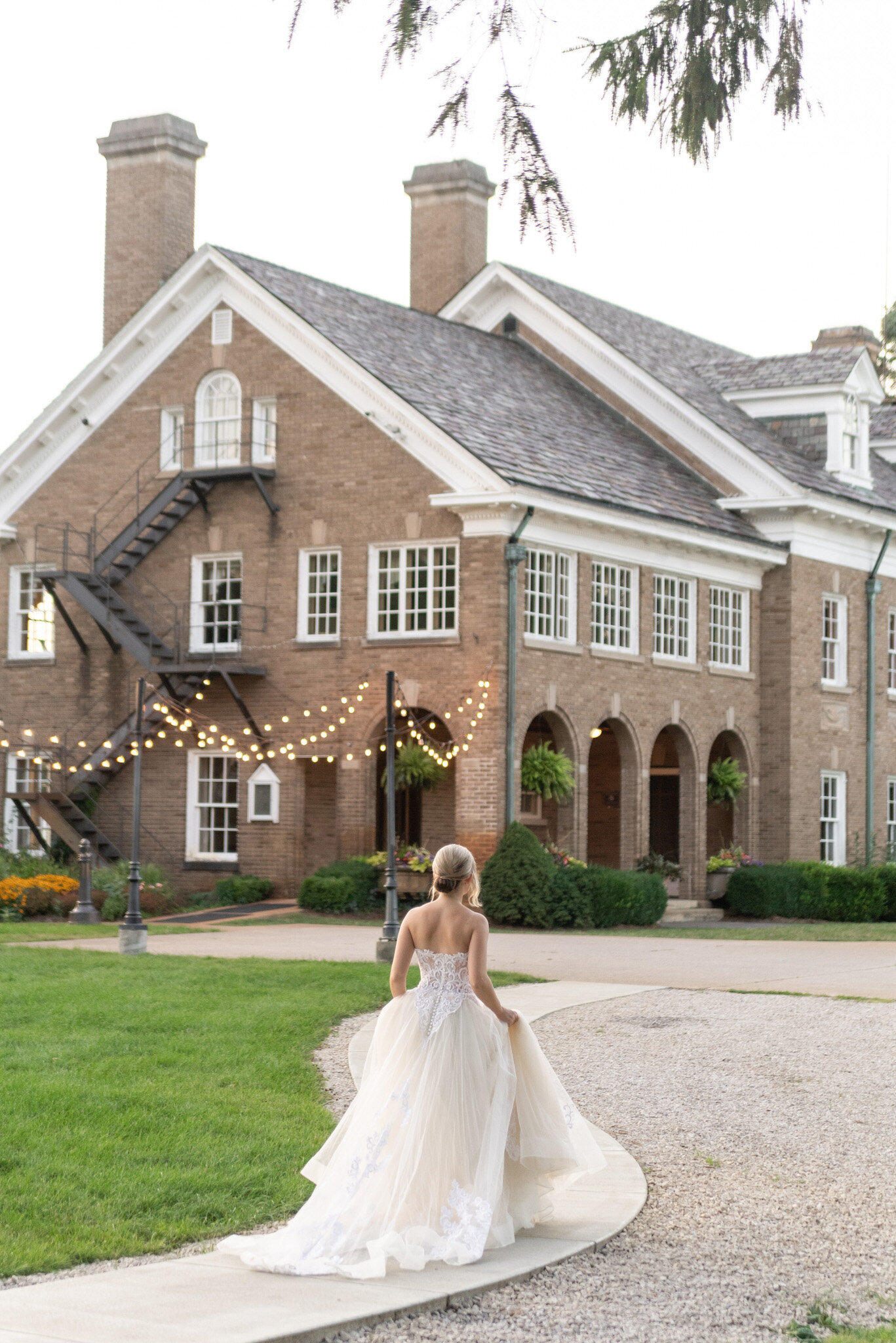 woman in a wedding dress walking towards a mansion