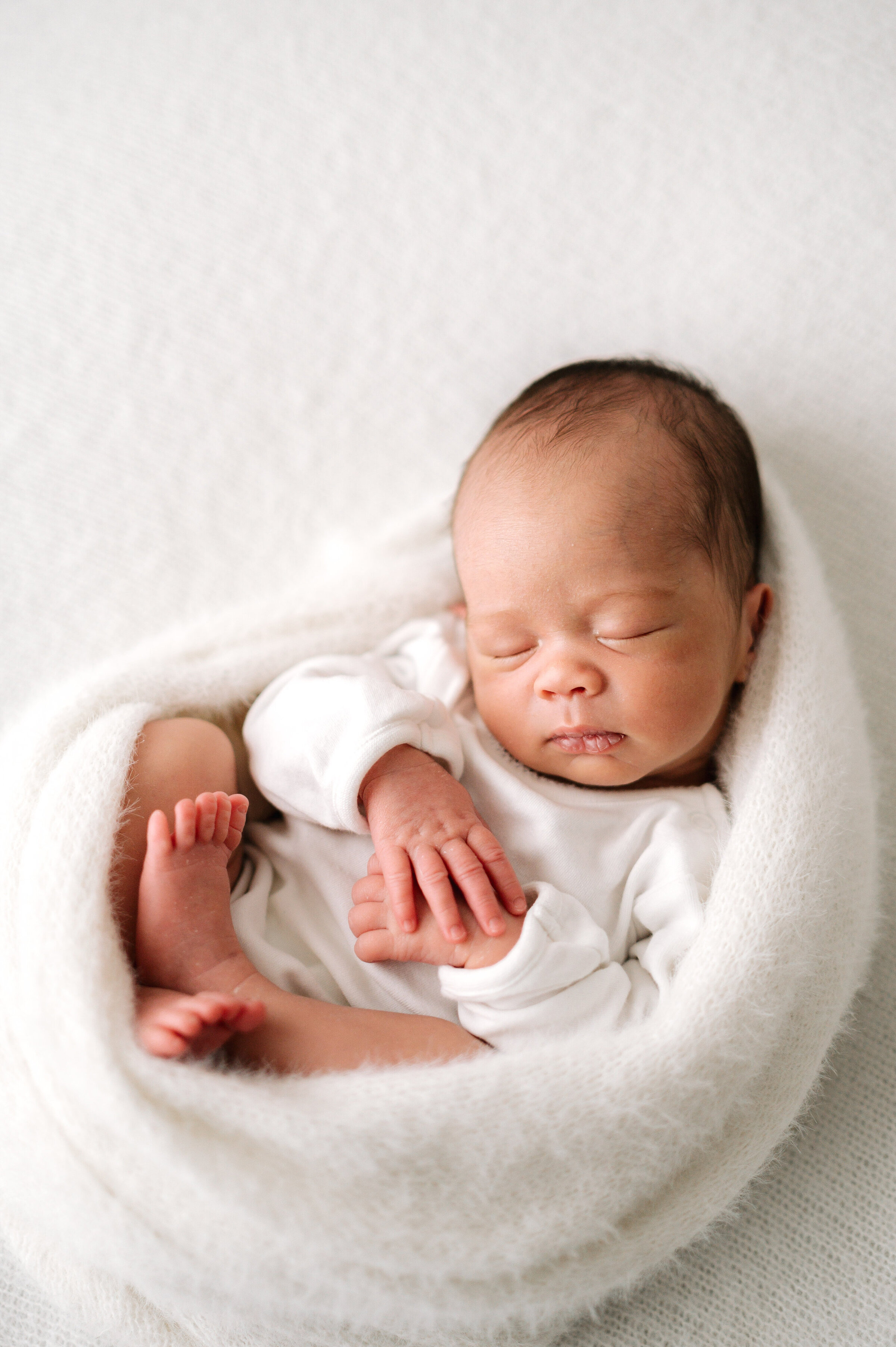 A newborn girl sleeping in a white blanket at Billingshurst photoshoot